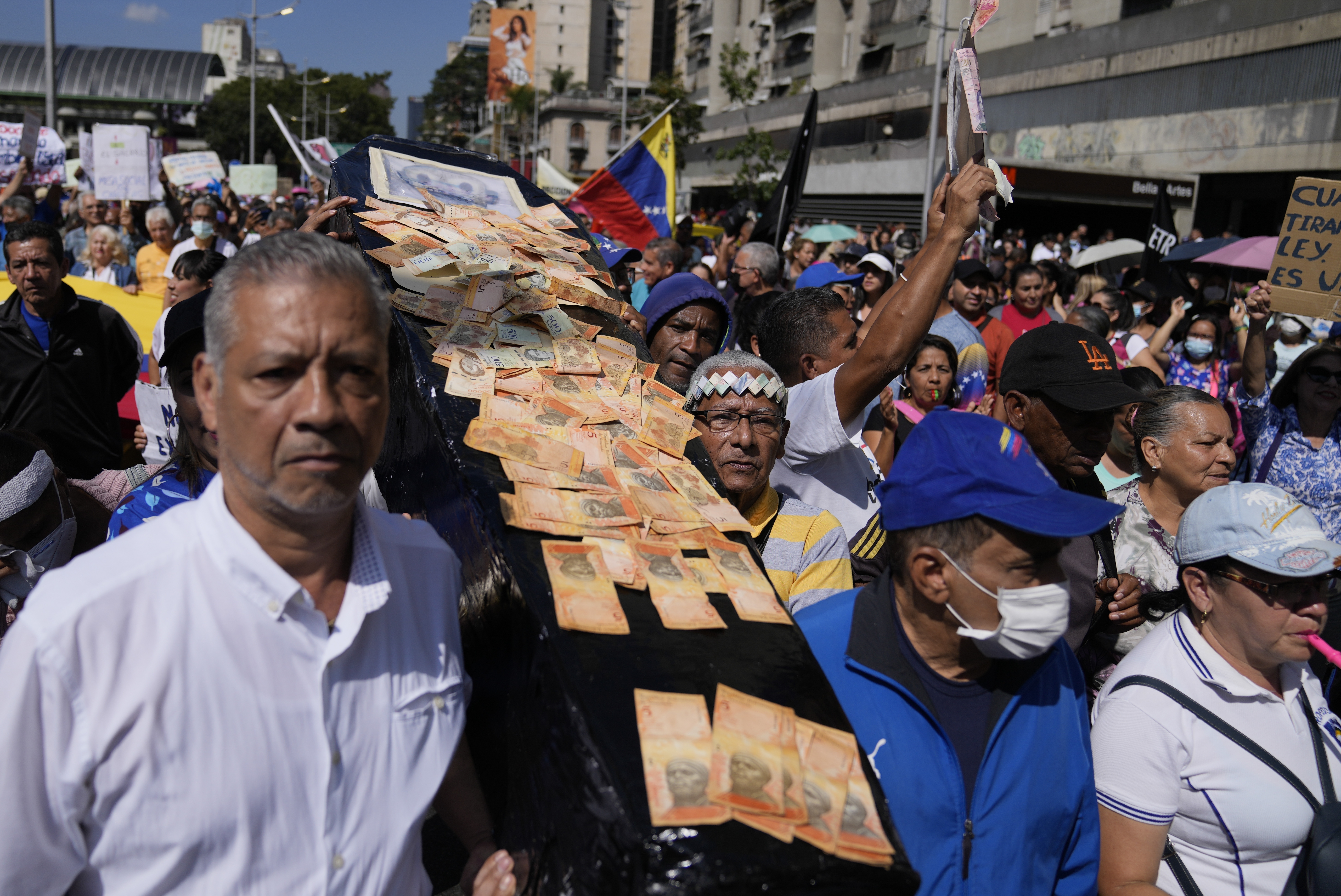 Trabajadores cargan un ataúd falso cubierto con billetes de bolívar mientras protestan por mejores salarios y beneficios en Caracas, Venezuela, el miércoles 11 de enero de 2023. (AP Foto/Ariana Cubillos)