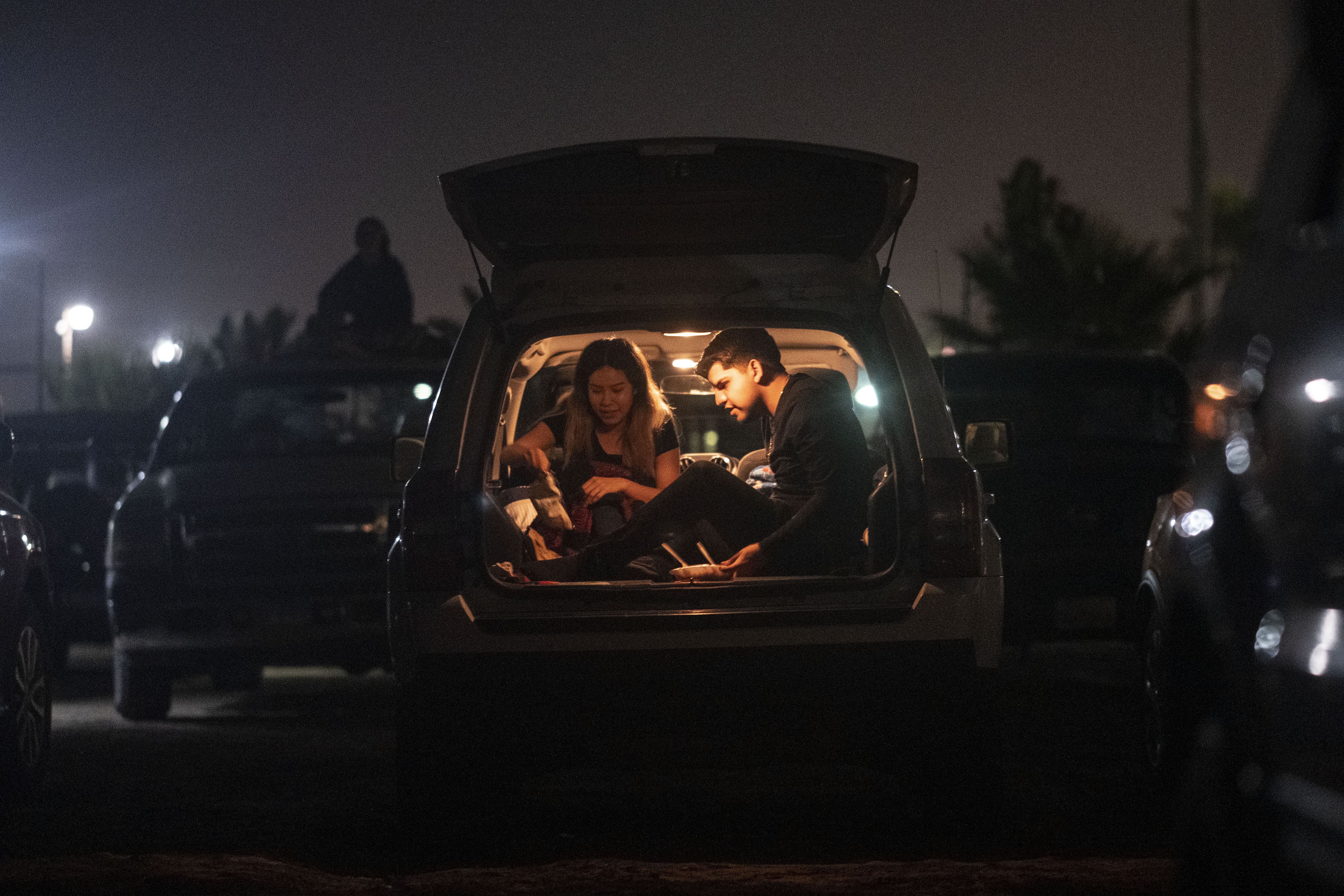 Una pareja come desde el carro mientras disfrutan una película en Playas de Rosarito, estado de Baja California, México, el 17 de julio de 2020, en medio de la nueva pandemia de coronavirus. (Foto de Guillermo Arias / AFP)