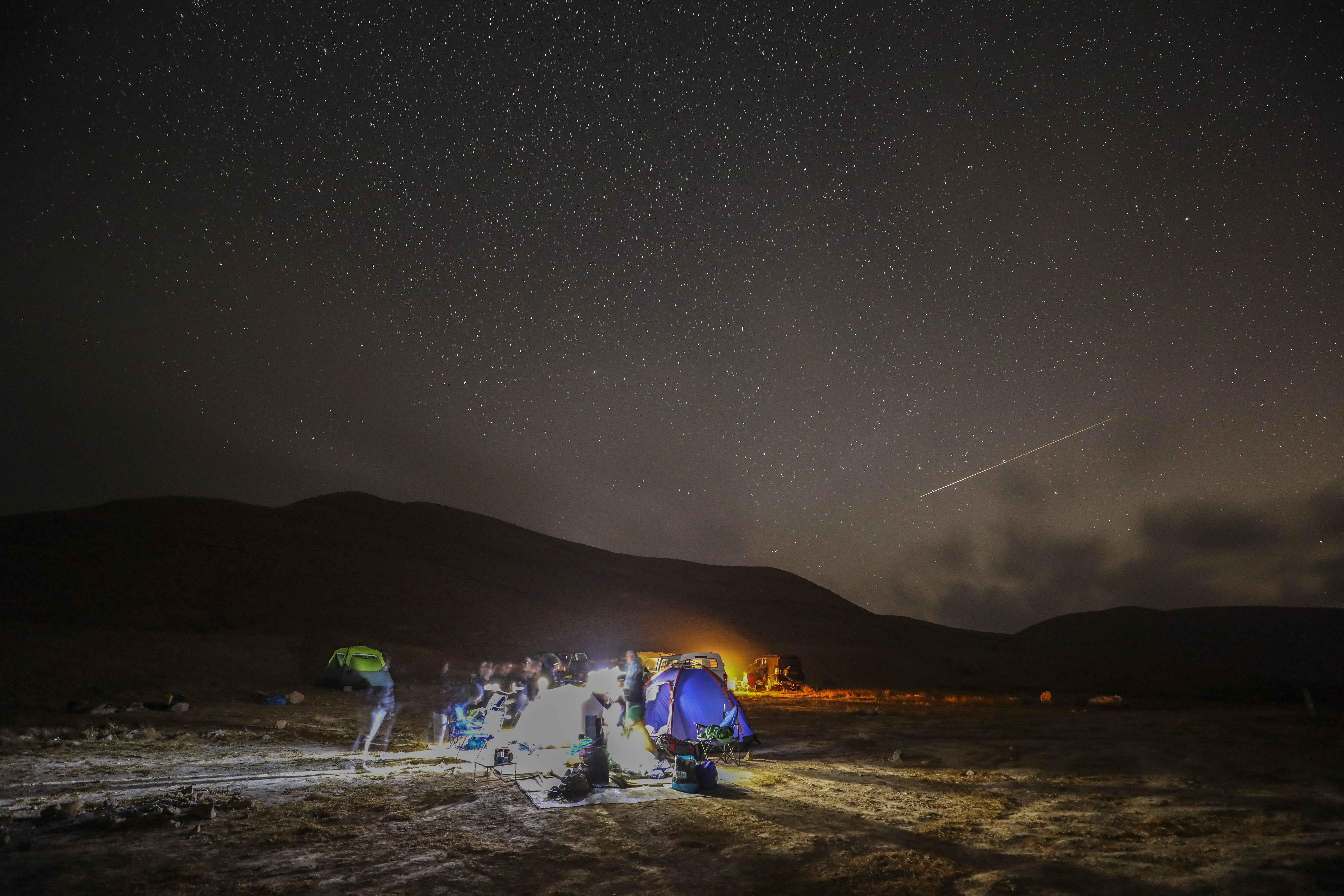 Un meteoro de las Perseidas surca el cielo sobre un camping en el desierto del Néguev, Israel (Foto de MENAHEM KAHANA / AFP)