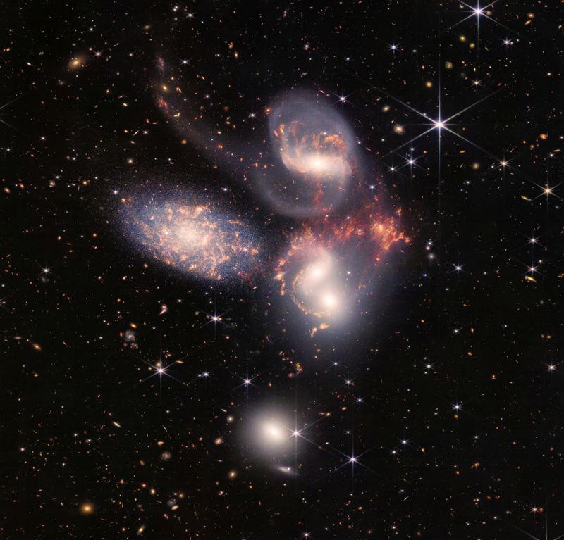 Un grupo de cinco galaxias que aparecen cerca unas de otras en el cielo: dos en el centro, una hacia la parte superior, una hacia la parte superior izquierda y una hacia la parte inferior se ven en un mosaico o compuesto de datos del infrarrojo cercano y medio del telescopio espacial James Webb de la NASA
