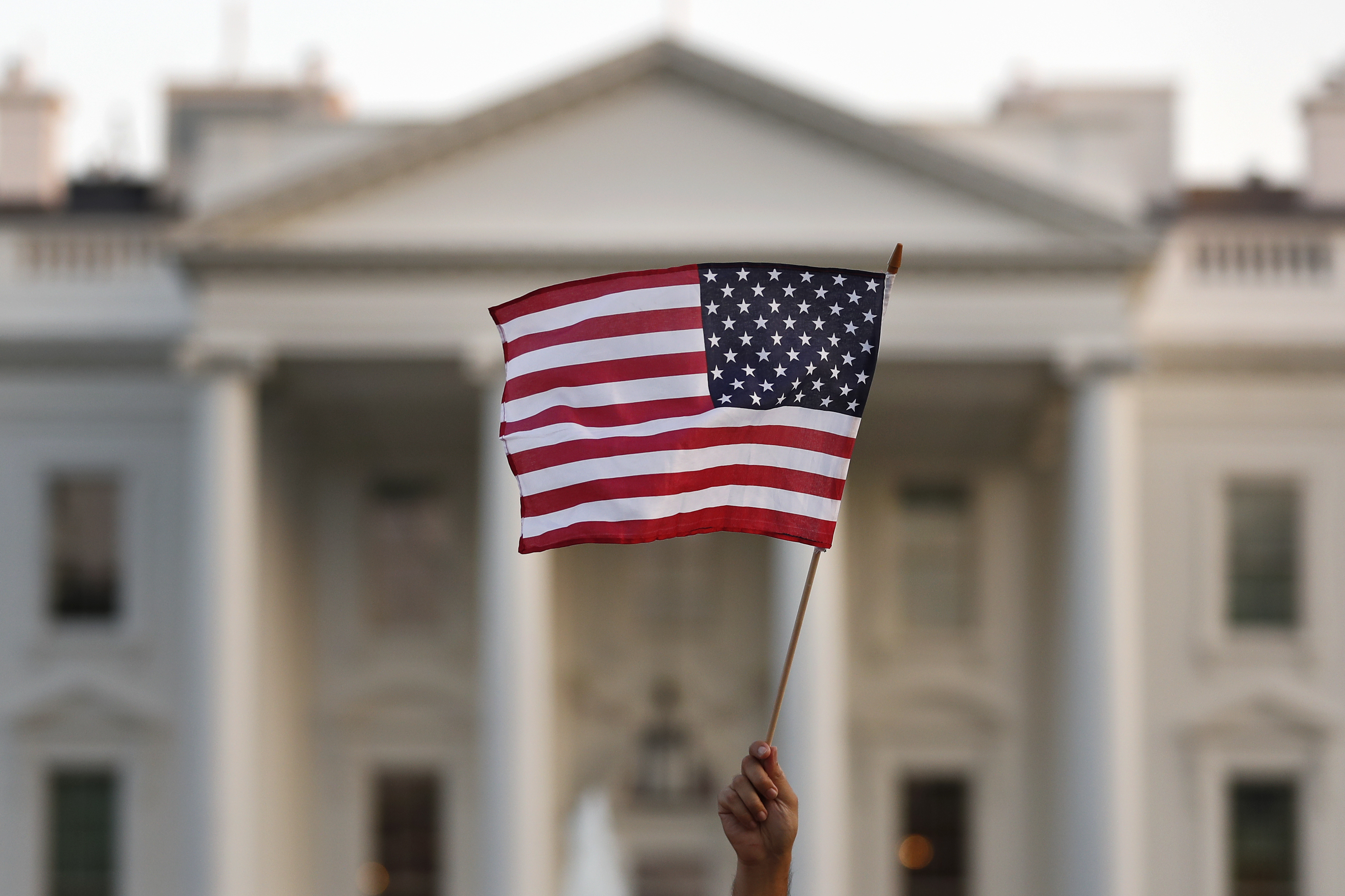 En esta imagen de septiembre de 2017, una persona ondea una bandera estadounidense a las afueras de la Casa Blanca, en Washington. (AP Foto/Carolyn Kaster/Archivo)