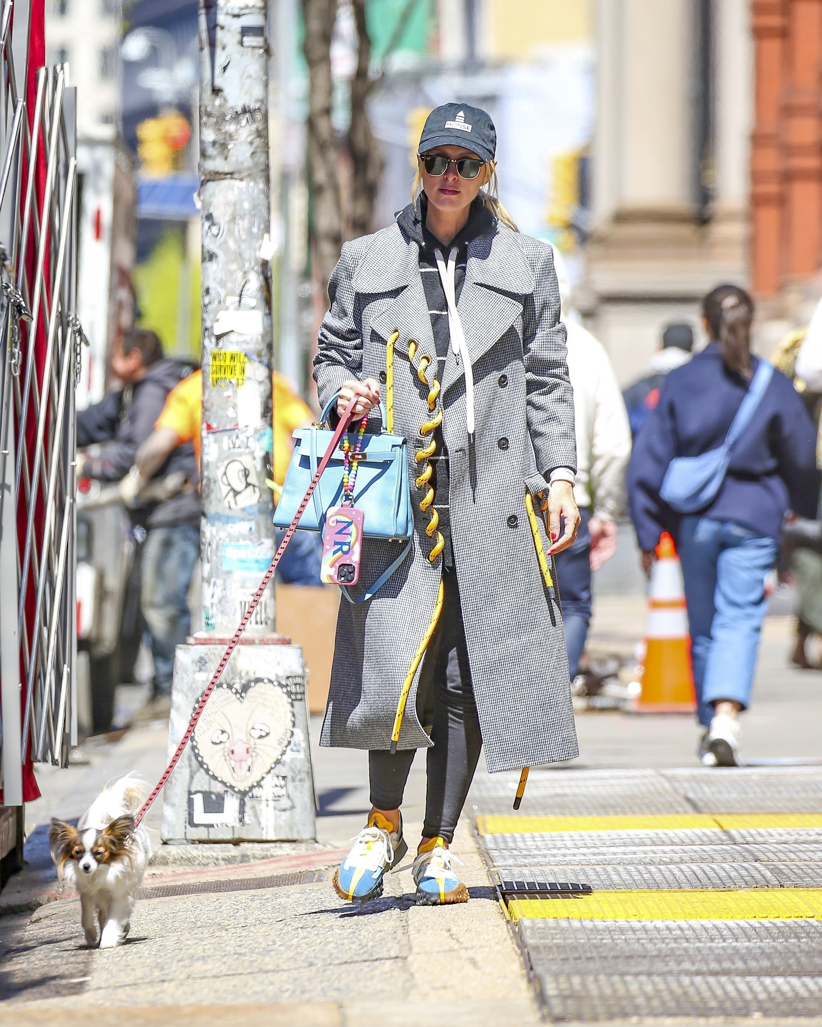 Nicky Hilton fue fotografiada mientras paseaba a su perro por las calles de Manhattan, en Nueva York. Lució un tapado gris con grandes cuerdas amarillas, una cartera turquesa, y llevó lentes de sol y gorra para pasar desapercibida