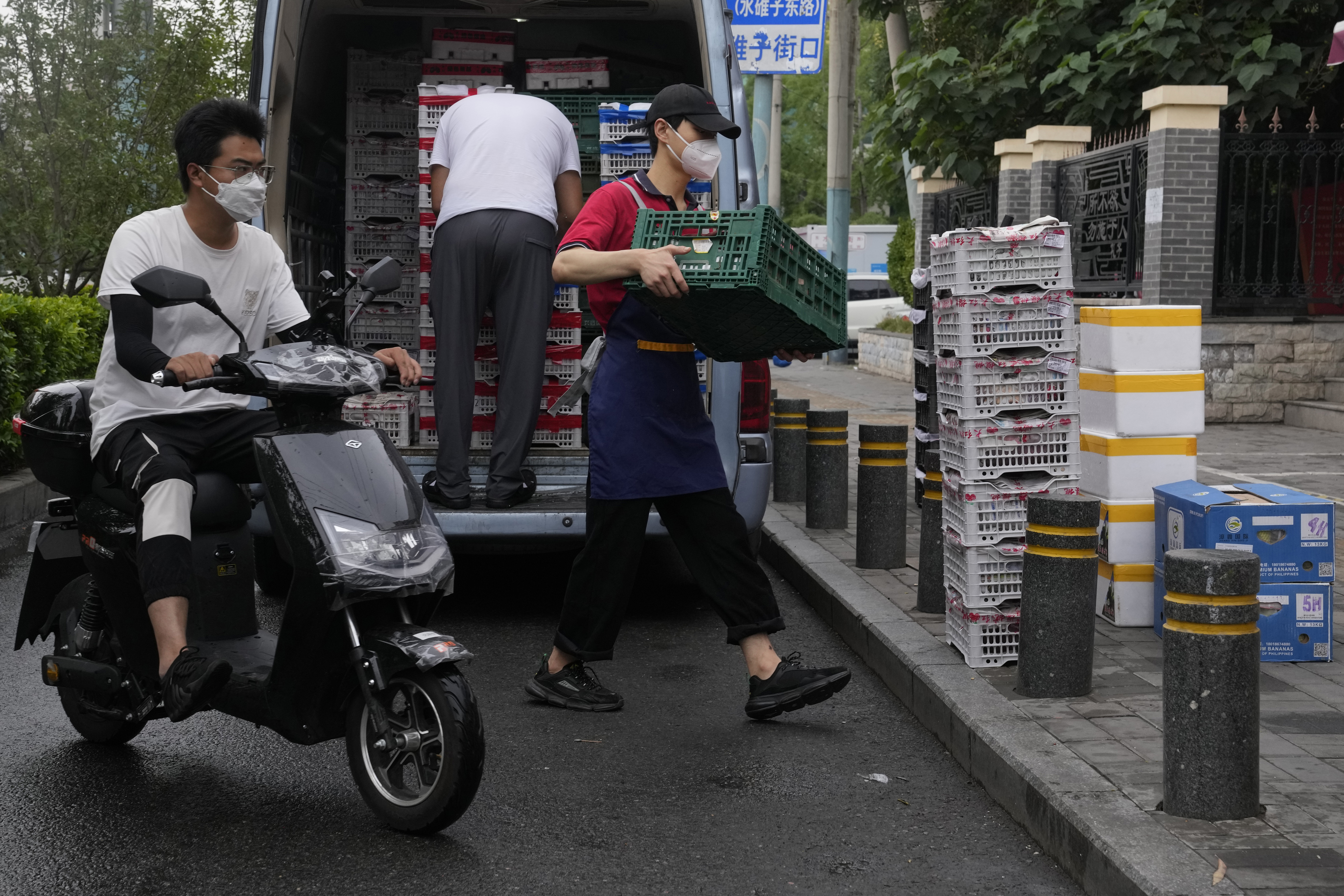 Un trabajador con una máscara descarga contenedores de fruta de una camioneta, el lunes 27 de junio de 2022, en Beijing. (Foto AP/Ng Han Guan)