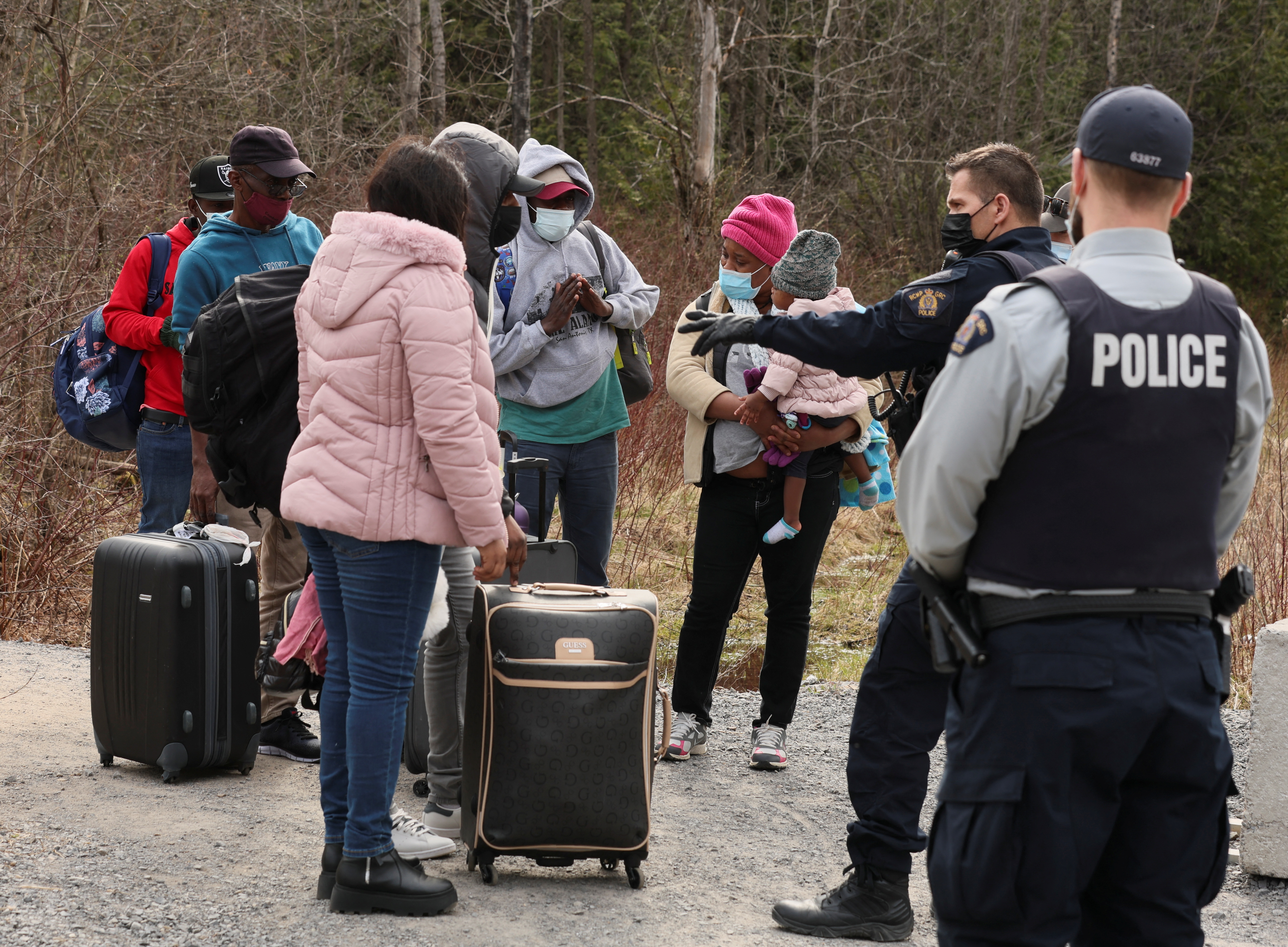 Asylum seekers cross into Canada near a checkpoint on Roxham Road
