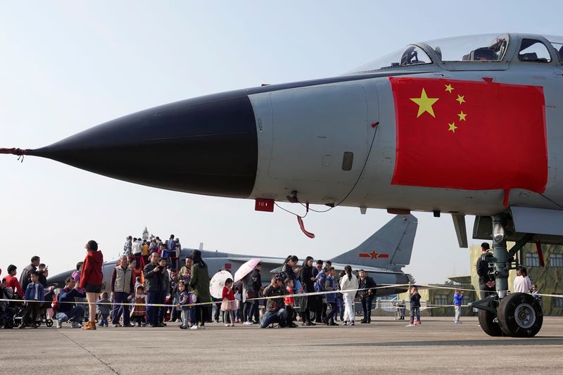 Foto de archivo de visitantes observando aviones de combate expuestos en una jornada de puertas abiertas un día antes del 70º aniversario de la fundación de la Fuerza Aérea del Ejército Popular de Liberación (EPL), en una base militar en Hangzhou, provincia de Zhejiang, China (REUTERS)