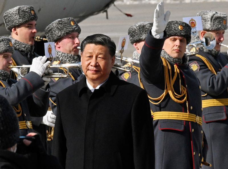 El presidente chino, Xi Jinping, camina junto a guardias de honor y miembros de una banda militar durante una ceremonia de bienvenida a su llegada a un aeropuerto en Moscú, Rusia (Kommersant Photo/Anatoliy Zhdanov vía REUTERS)
