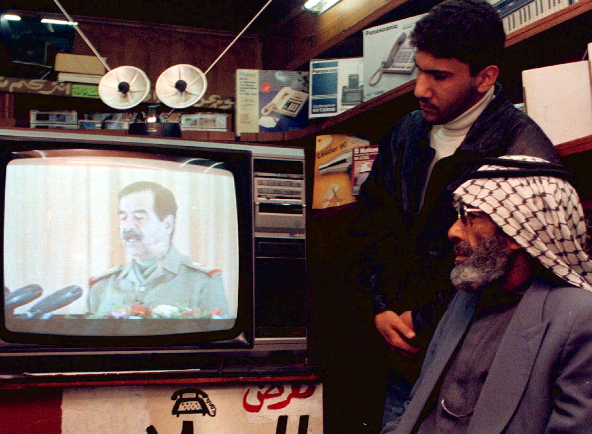 Un comerciante y su hijo siguen un discurso televisado del presidente iraquí Saddam Husein en el sexto aniversario de la guerra del Golfo, el 17 de enero de 1997 (REUTERS)