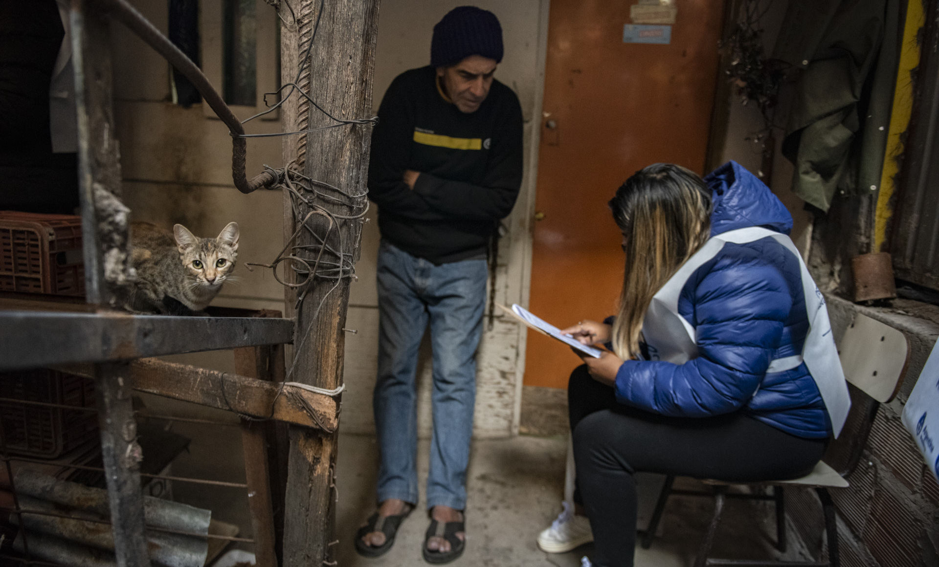 Carlos Acosta brinda sus datos a una censista, durante la entrevista realizada en la puerta de su pequeña casa de madera, en un primer piso