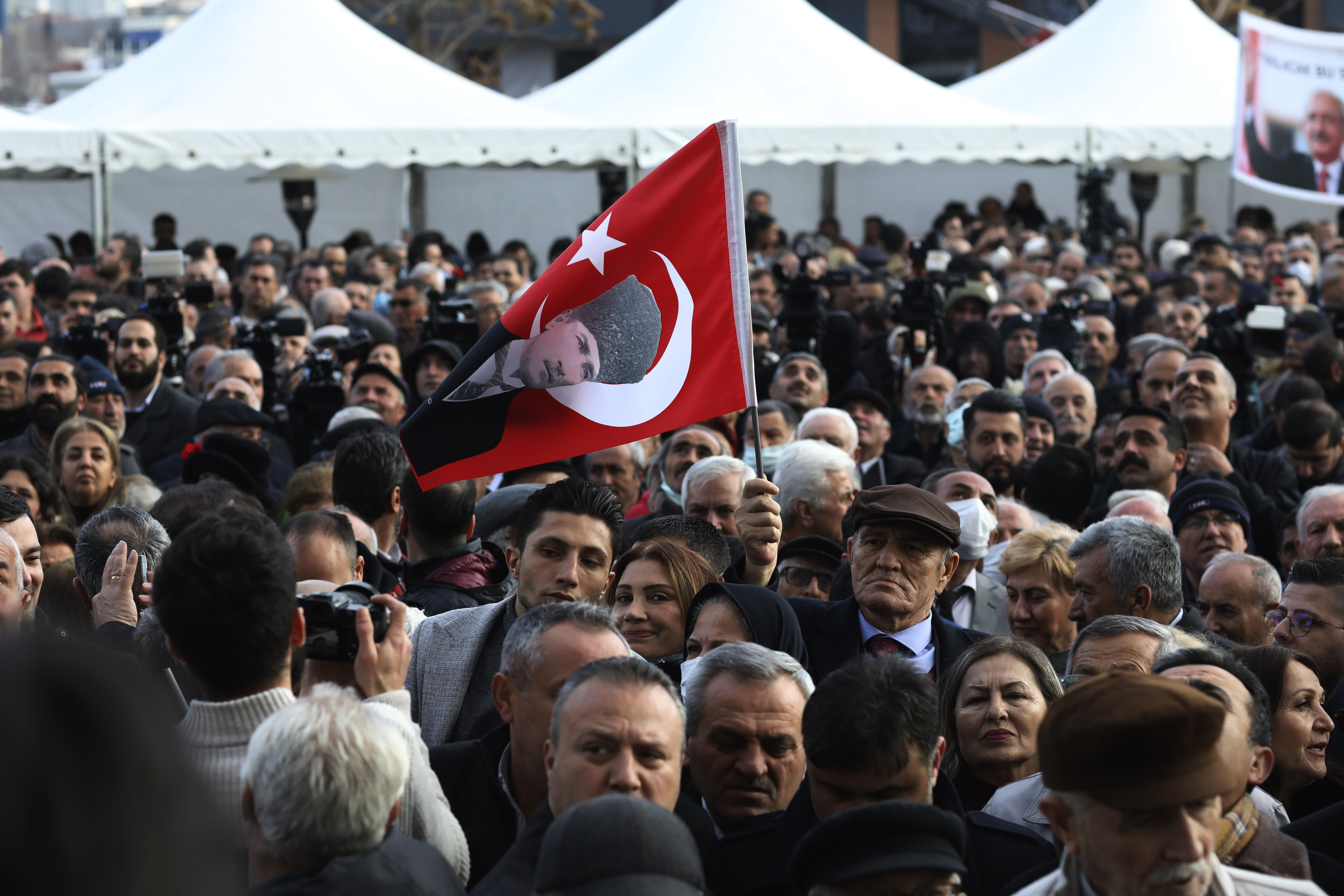 Un hombre sostiene una bandera con la imagen del fundador de Turquía, Mustafa Kemal Ataturk, mientras espera junto a otros partidarios de la oposición al nombramiento del candidato de una alianza electoral para hacer frente al presidente, Recep Tayyip Erdogan, en las próximas elecciones, en Ankara, Turquía, el 6 de marzo de 2023. (AP Foto/Burhan Ozbilici)