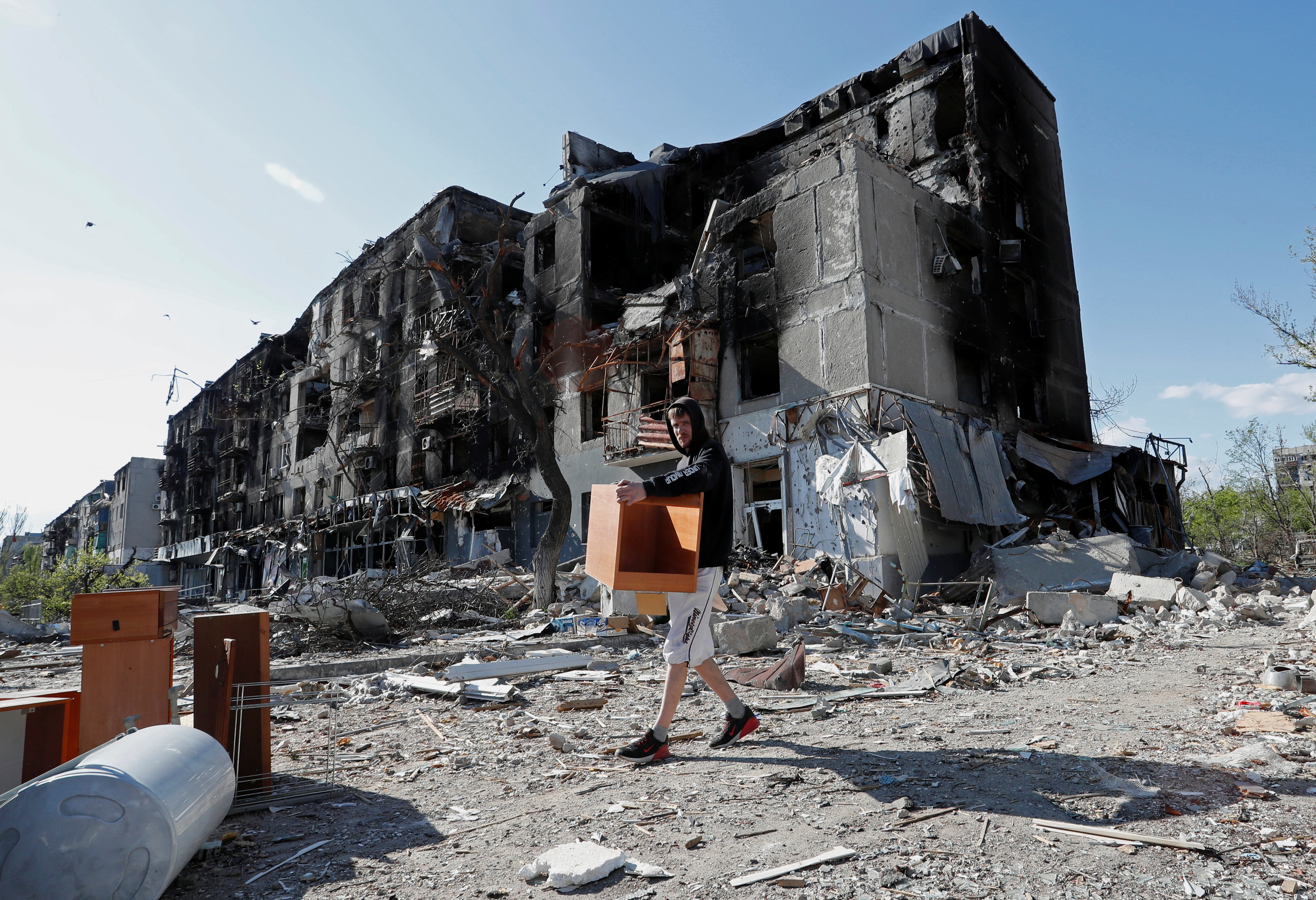 Un residente local saca muebles de un edificio de apartamentos gravemente dañado durante el conflicto entre Ucrania y Rusia en la ciudad portuaria sureña de Mariupol