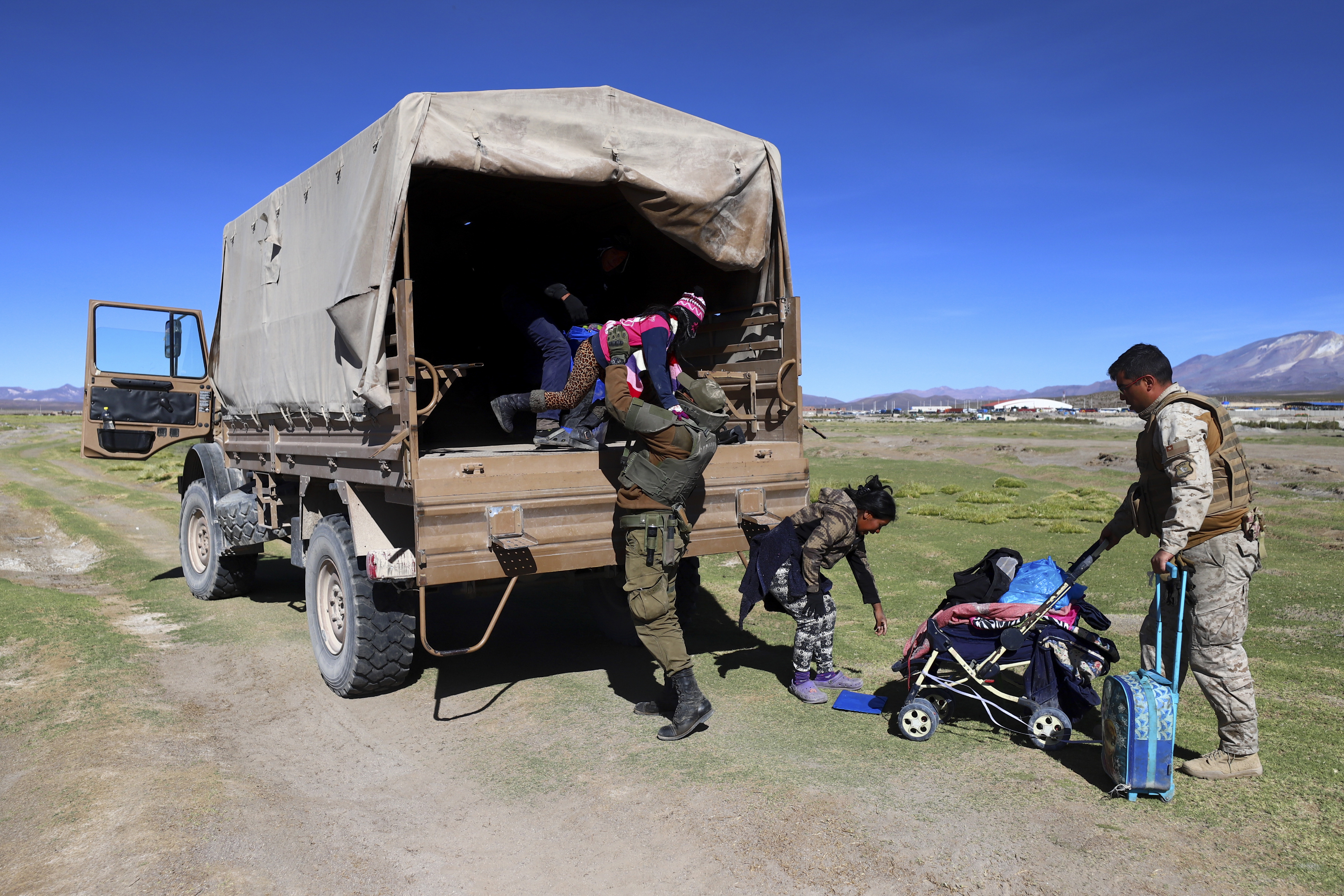 A Chilean soldier helps a young migrant into a military truck near Colchane, Chile, Wednesday, March 1, 2023, as soldiers take a migrant family to a shelter where police search.  The government announced an increase in the presence of the military on the border with Peru and Bolivia as a measure to curb illegal immigration.  (AP Photo/Ignacio Munoz)