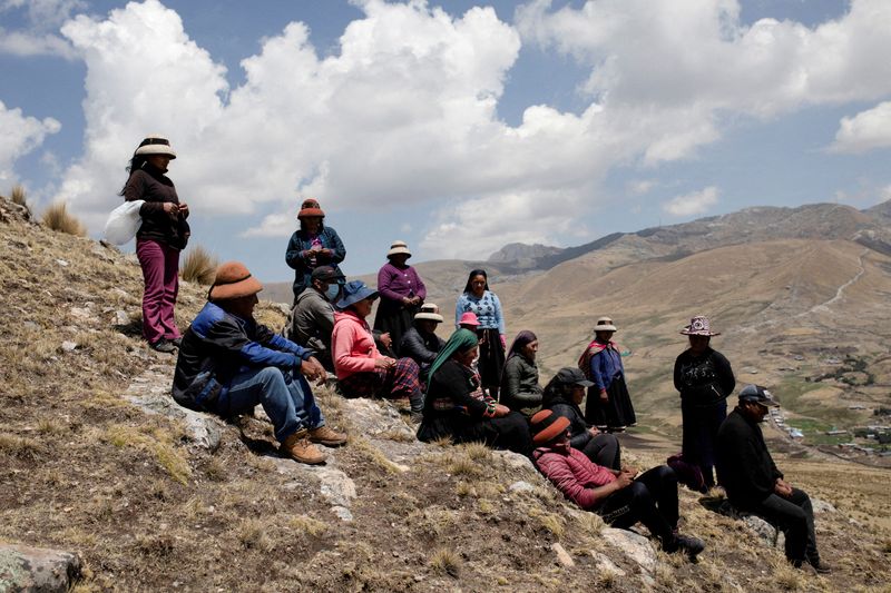 FOTO DE ARCHIVO: Personas sentadas en las montañas frente a una mina operada por MMG Las Bambas, en una región donde los lugareños afirman que la actividad minera ha afectado negativamente al rendimiento de los cultivos y ha matado al ganado, en las afueras de Cusco, Perú. 14 de octubre de 2021. REUTERS/Angela Ponce/