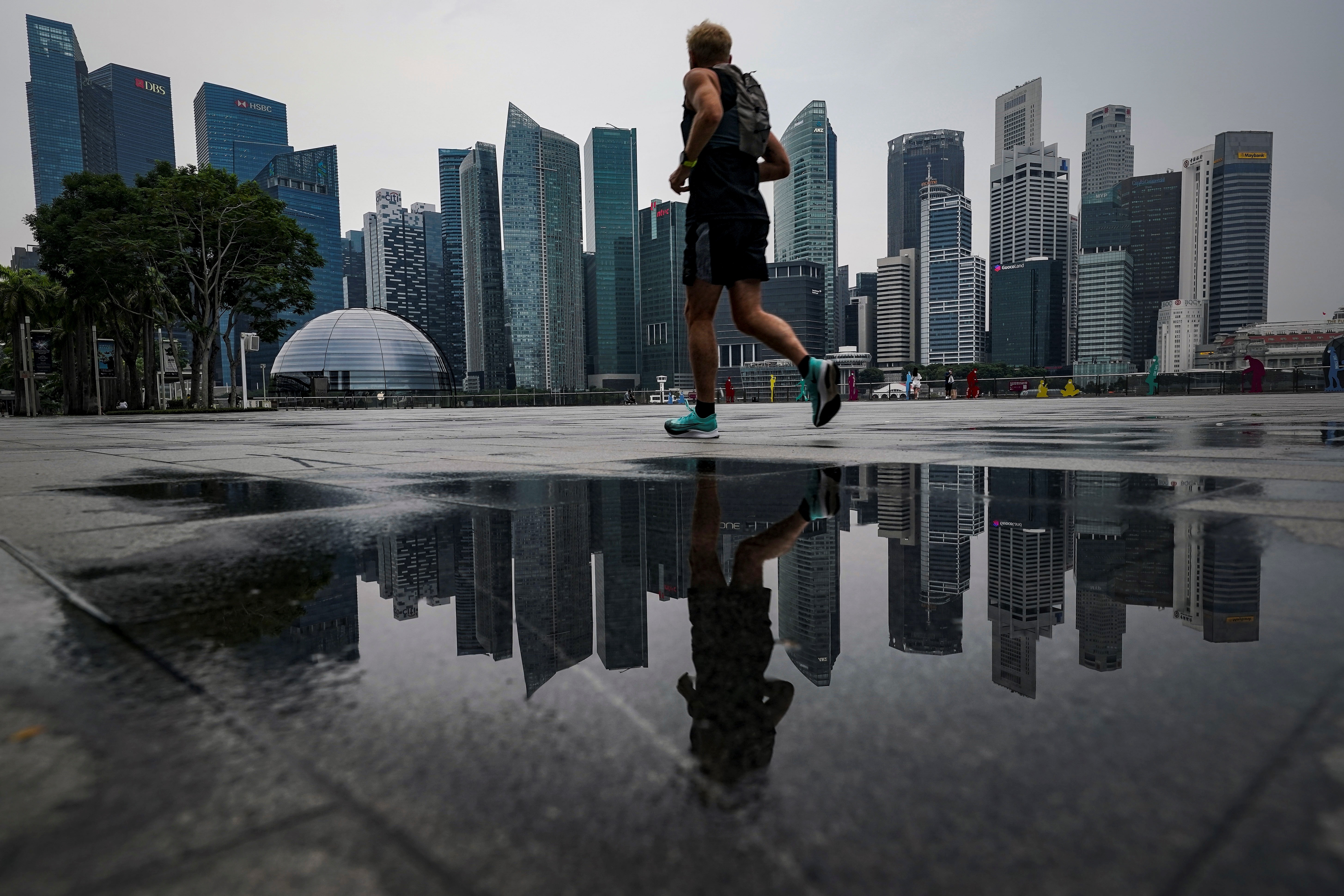 Un corredor pasa por el horizonte del distrito financiero a través de la bahía de Marina en Singapur. EFE/EPA/WALLACE WOON
