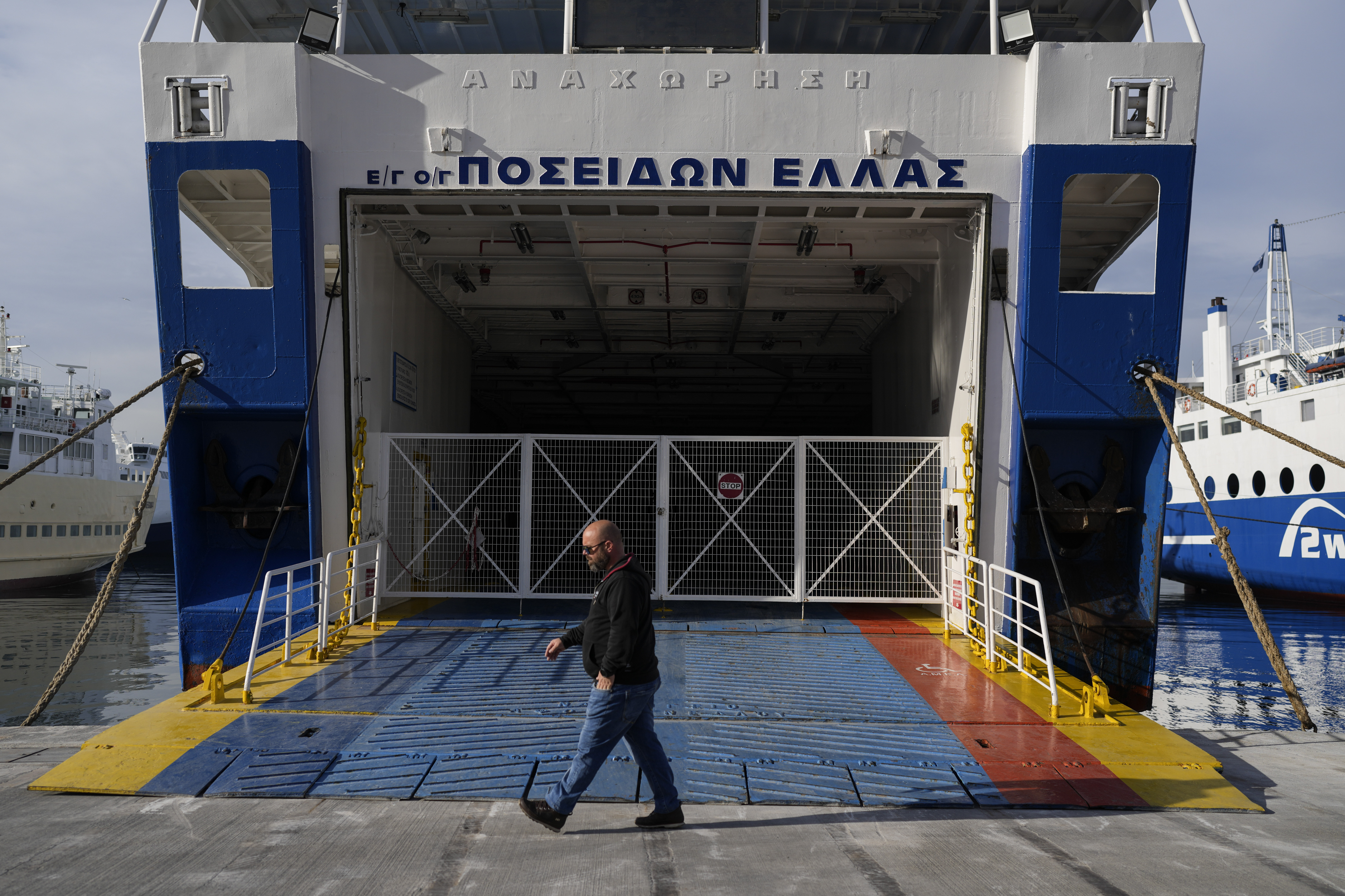 A man walks past the entrance ramp to a ferry moored at the port of Piraeus during a 24-hour general strike, on March 16, 2023. (AP Photo/Petros Giannakouris)