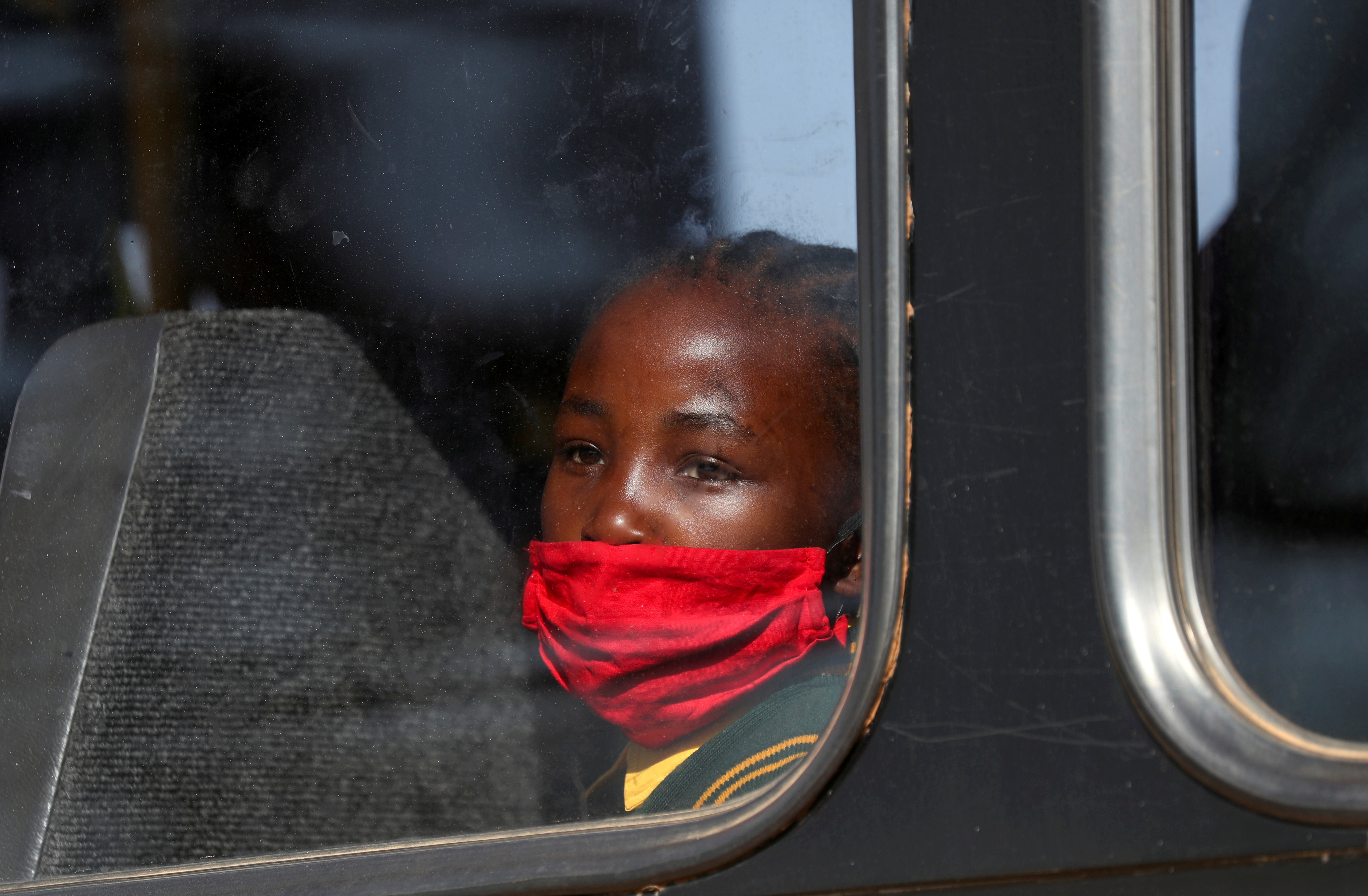 FOTO DE ARCHIVO: Una niña con una máscara protectora mira a través de la ventana de un autobús en Eikenhof, al sur de Johannesburgo, Sudáfrica, 24 de agosto de 2020. REUTERS / Siphiwe Sibeko /