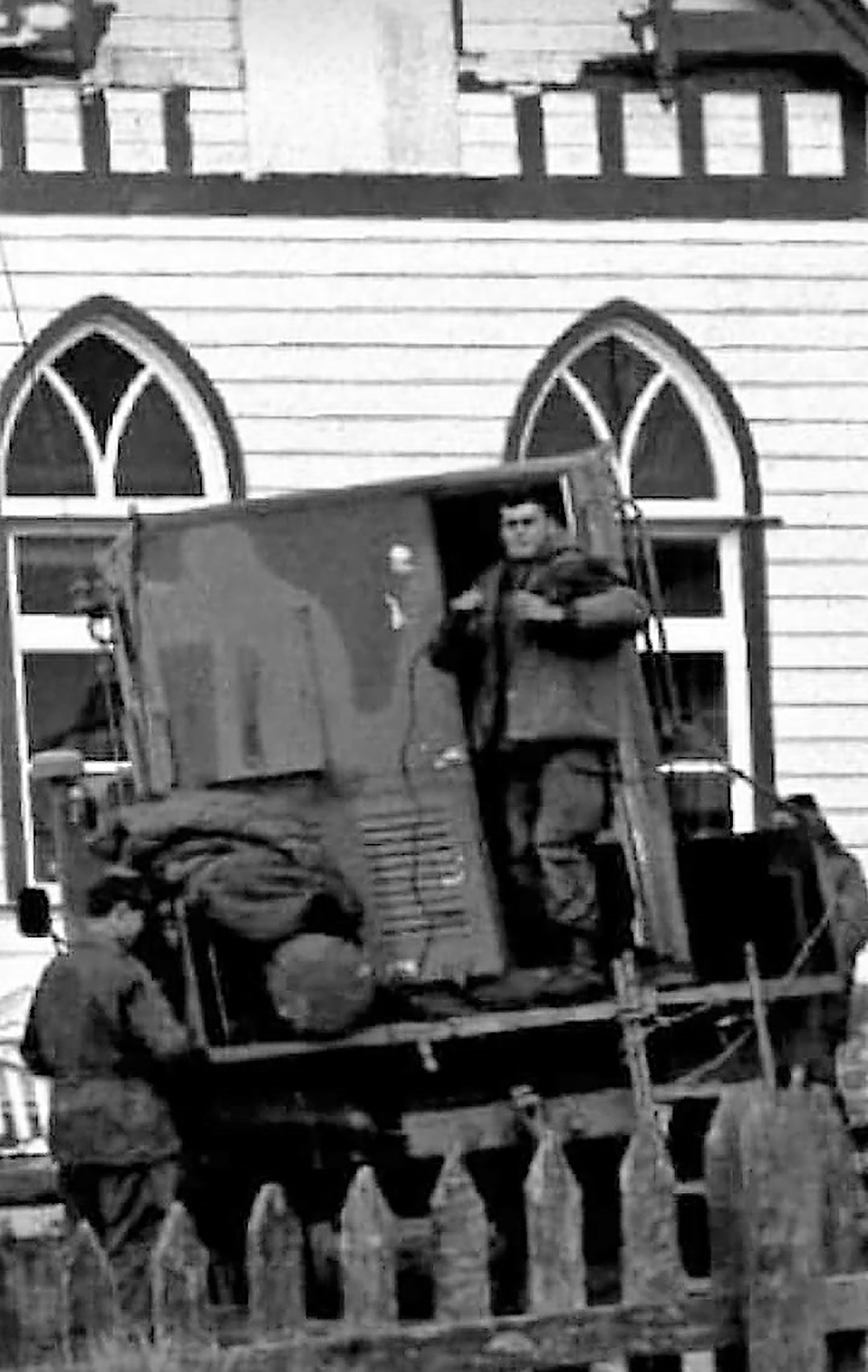 Oscar Bauchi, sobre un vehículo en la única fotografía que tiene en Malvinas. Detrás está la iglesia de Puerto Argentino.