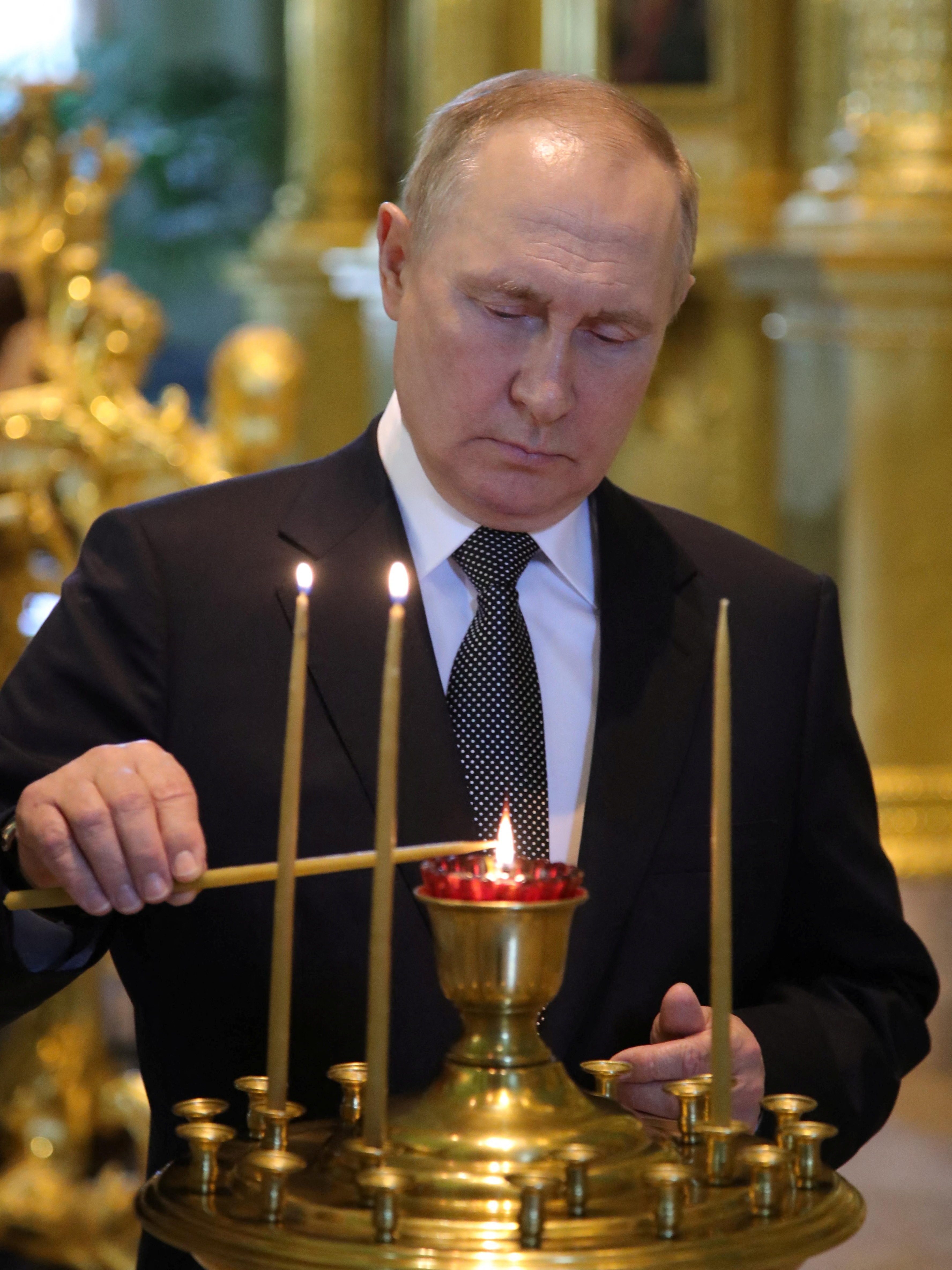 Vladímir Putin enciende una vela en la catedral de Pedro y Pablo tras la ceremonia de firma del Día de la Armada en San Petersburgo, Rusia, el 31 de julio de 2022 (Reuters) 