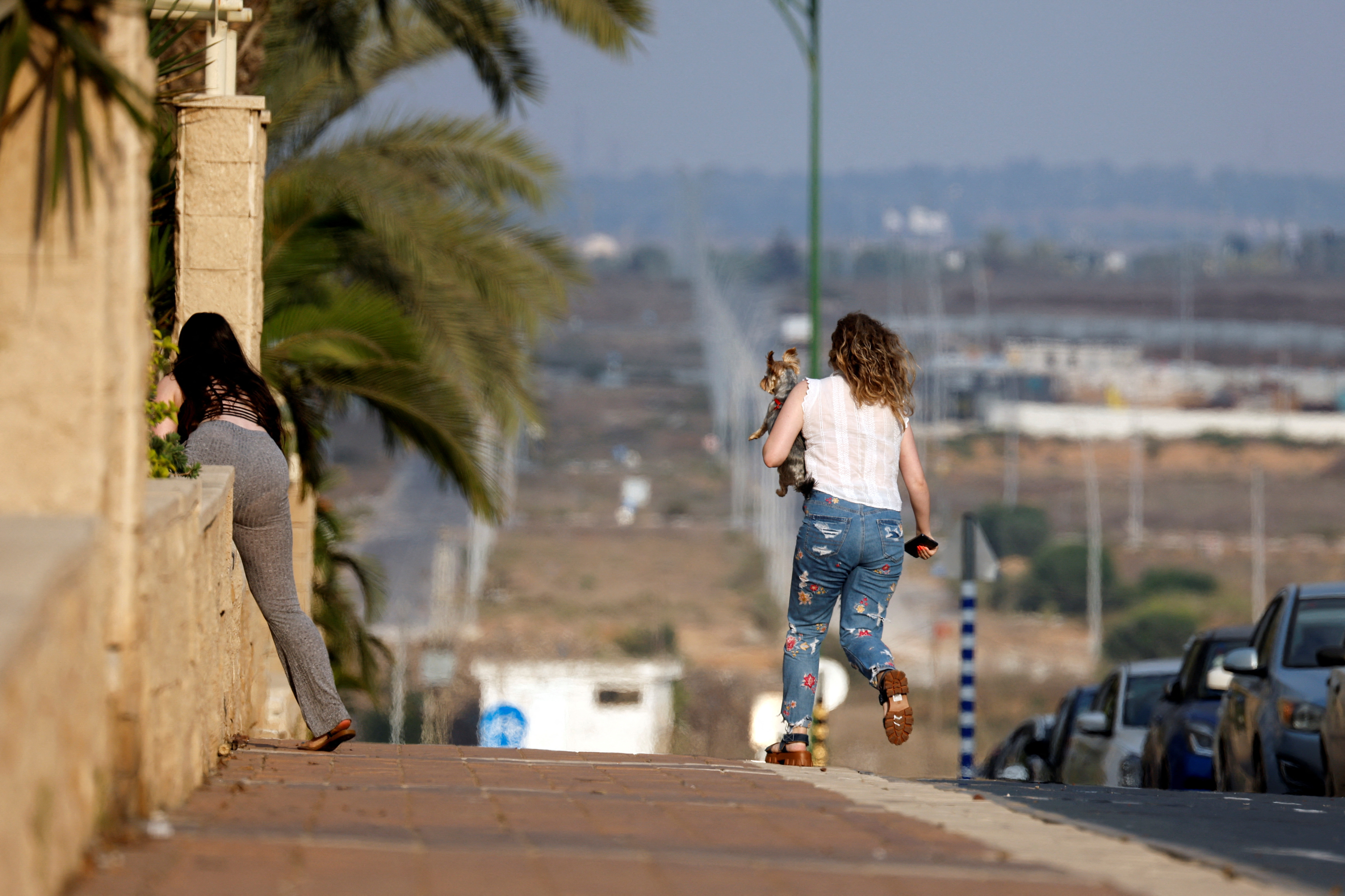 Israeli women run as sirens signaling rockets from Gaza are heard in Ashkelon, Israel, on August 6, 2022.  REUTERS/Amir Cohen
