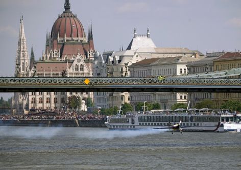 Hungarian pilot and world champion Peter Besenyei flies under the oldest Hungarian bridge, the 'Lanchid' (Chain Bridge) with his 'Corvus Racer' plane on May 1, 2015 during a flying and car show around the Danube River of Budapest downtown. AFP PHOTO / ATTILA KISBENEDEK (Photo credit should read ATTILA KISBENEDEK/AFP/Getty Images)