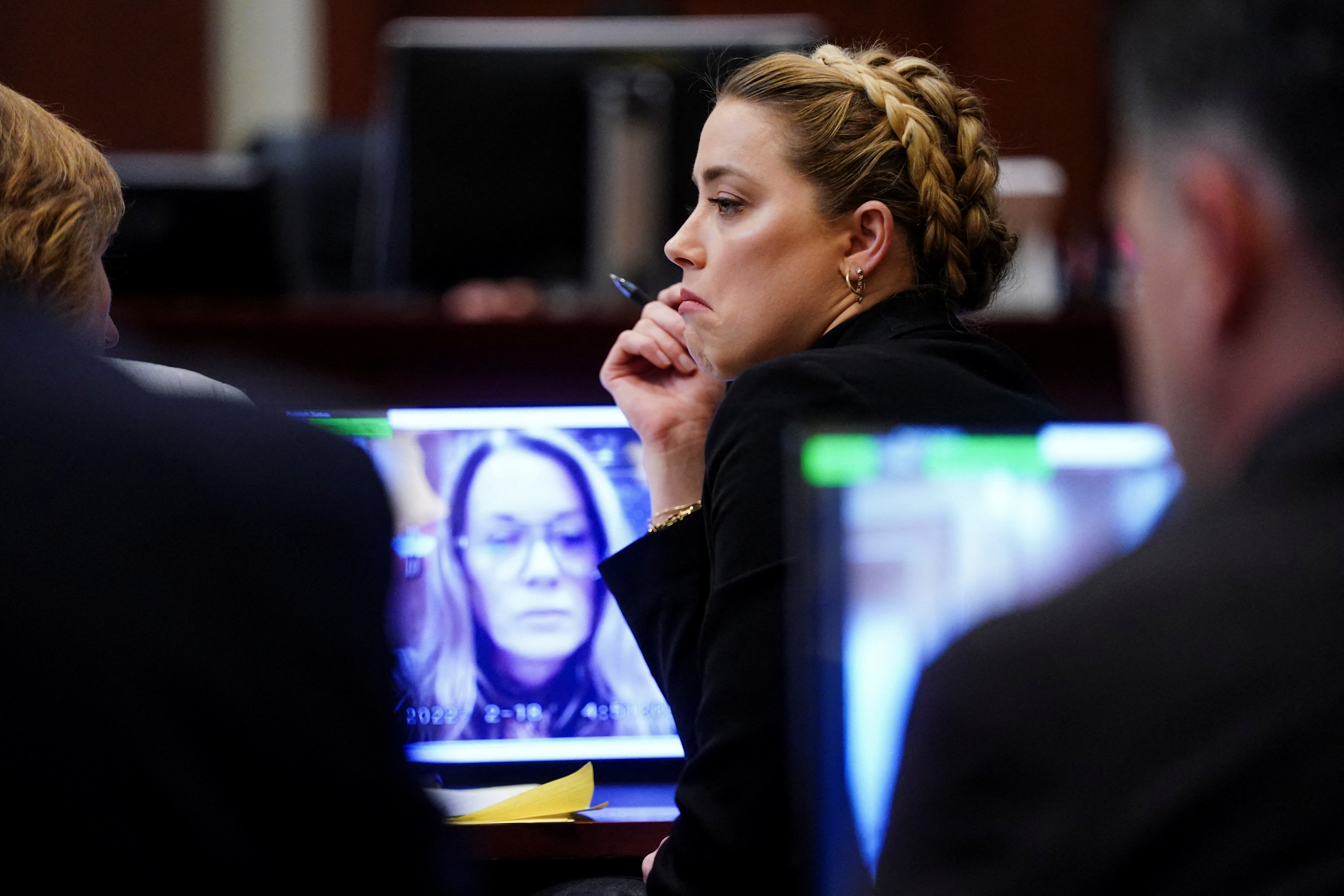 La actriz Amber Heard escucha a su ex asistente personal Kate James que testifica a través de un video durante el caso de difamación de Johnny Depp contra ella (Reuters)