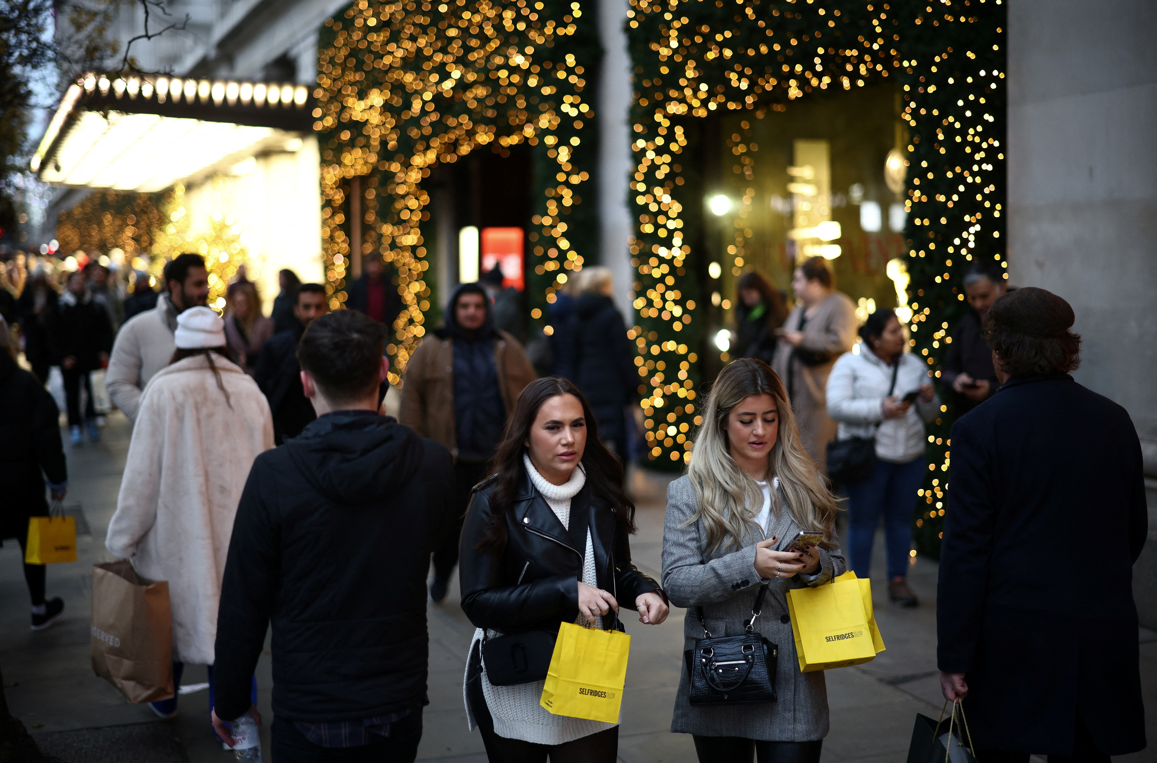 People carry shopping bags as they walk past Christmas themed shop displays on Oxford Street in London, December 4, 2022. REUTERS/Henry Nicholls