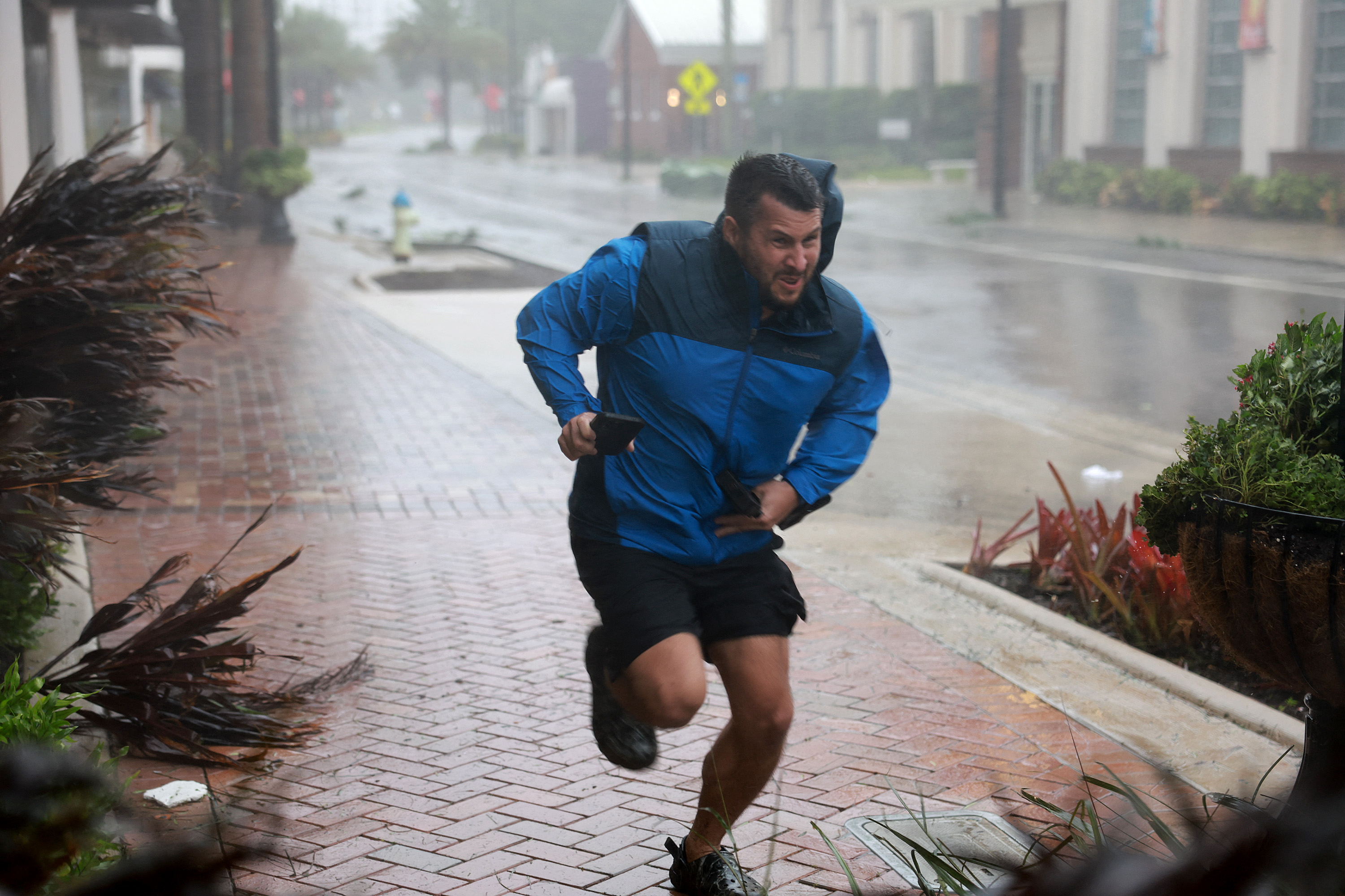Brent Shaynore corre hacia un lugar protegido a través del viento y la lluvia del huracán Ian en Sarasota, Florida. 
