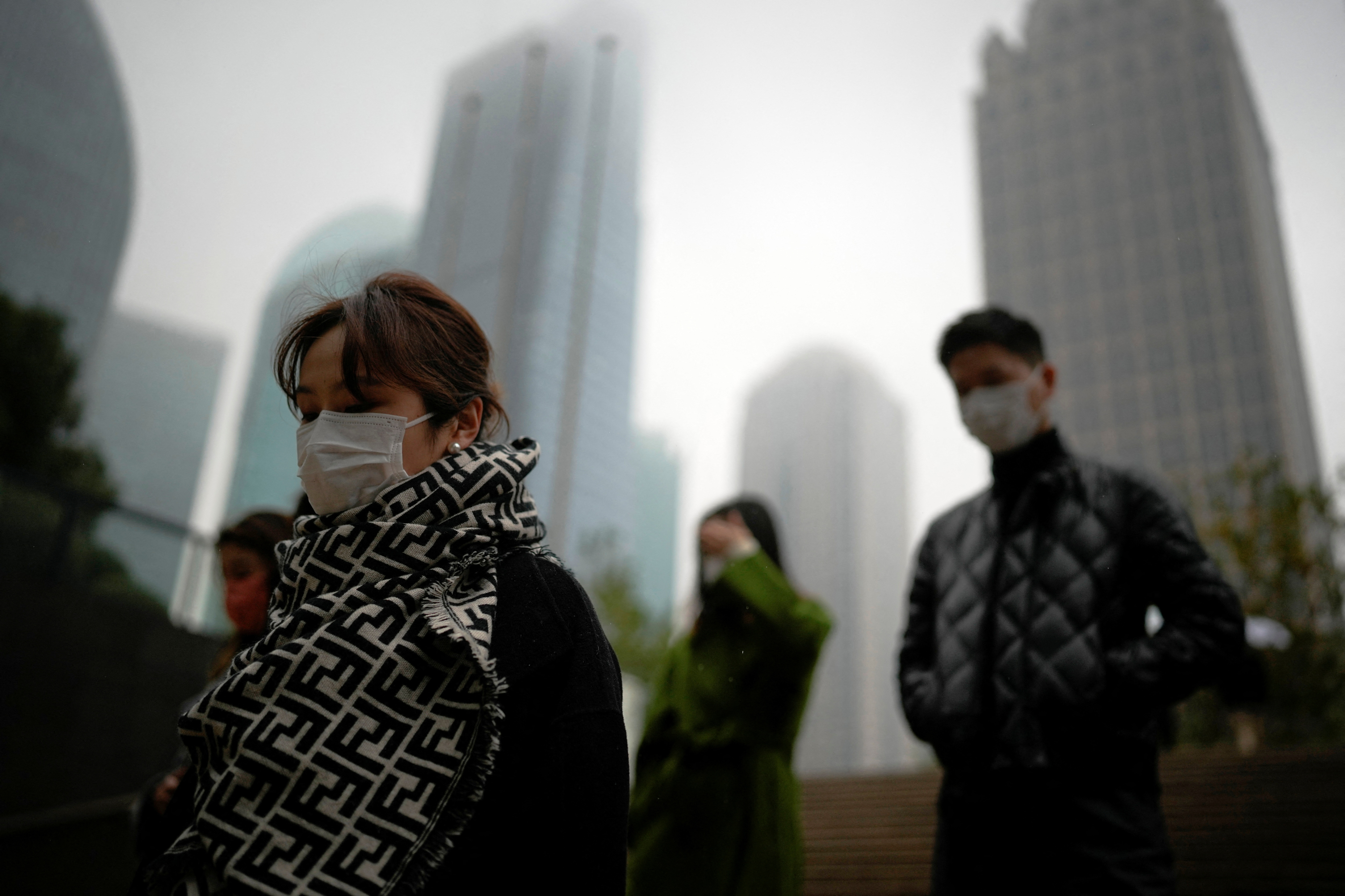 Personas con mascarillas caminan por el distrito financiero de Lujiazui, mientras continúan los brotes de la enfermedad por coronavirus (COVID-19) en Shanghái, China, 9 de diciembre de 2022. REUTERS/Aly Song