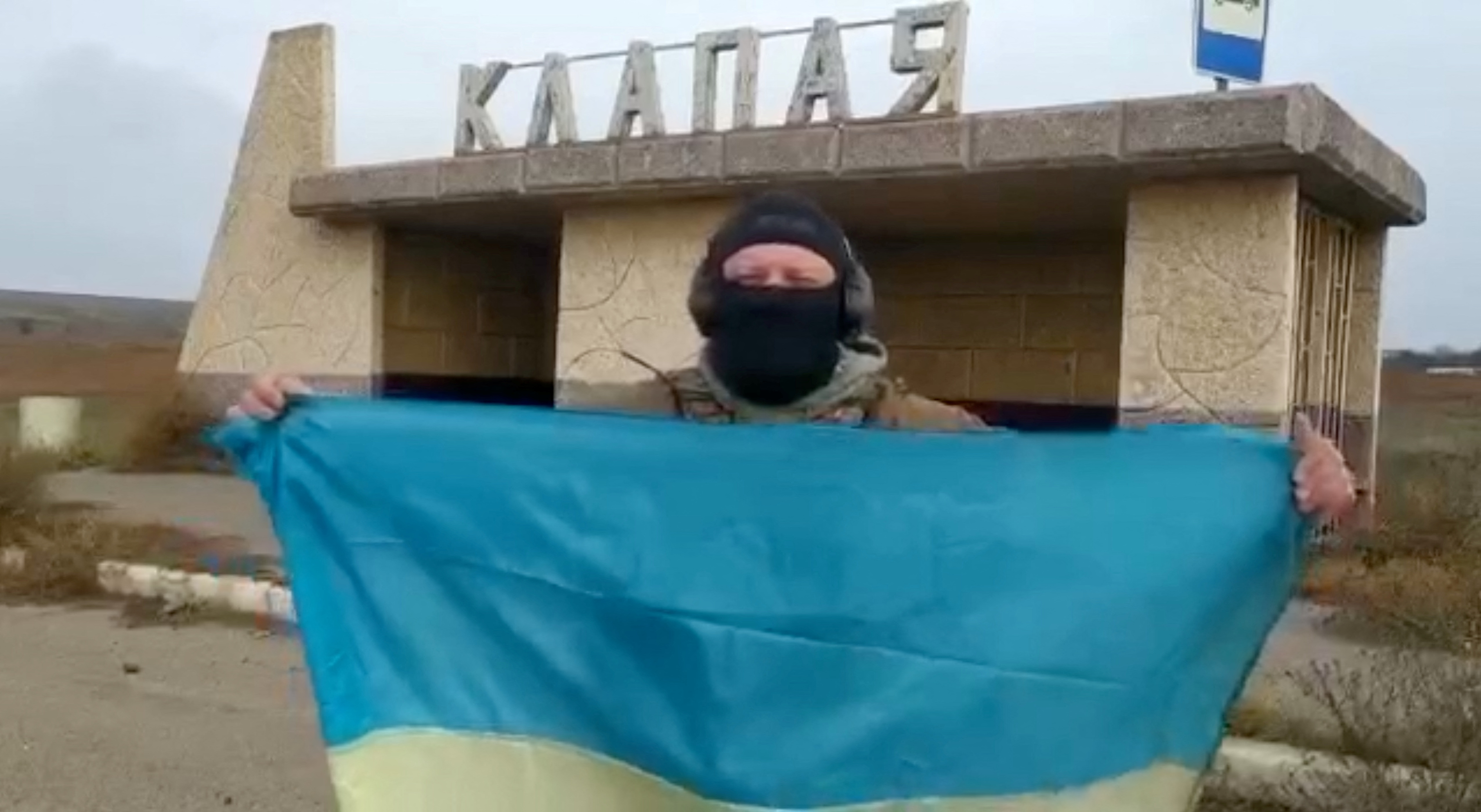 Un soldado ucraniano ondea la bandera nacional en el pueblo de Klapaya, en la región de Kherson, Ucrania, en esta captura de pantalla obtenida de un vídeo publicado el 11 de noviembre de 2022 (Reuters)