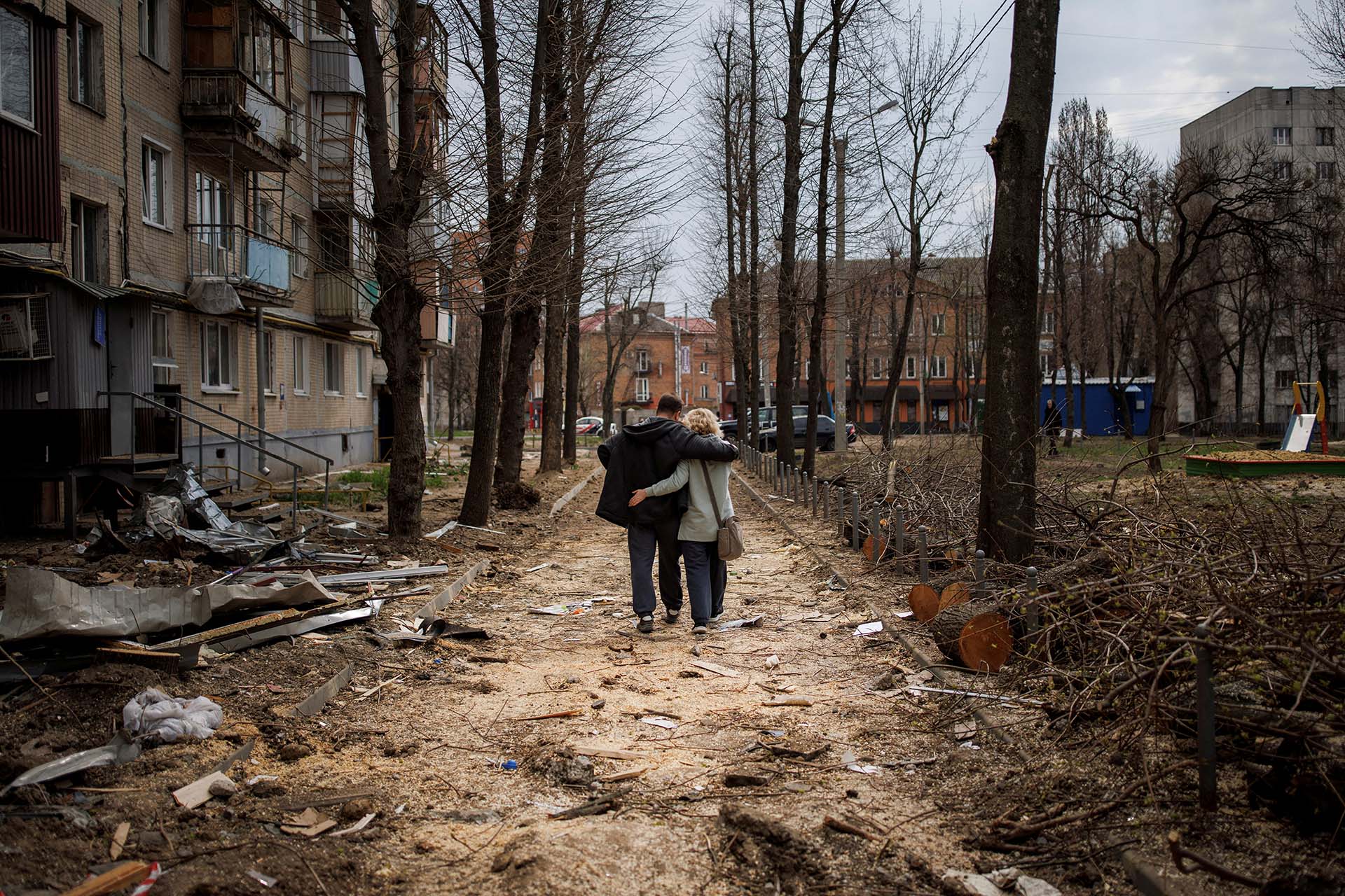 Una pareja camina abrazada entre edificios bombardeados por Rusia en la ciudad de Kharkiv, Ucrania (REUTERS/Alkis Konstantinidis)