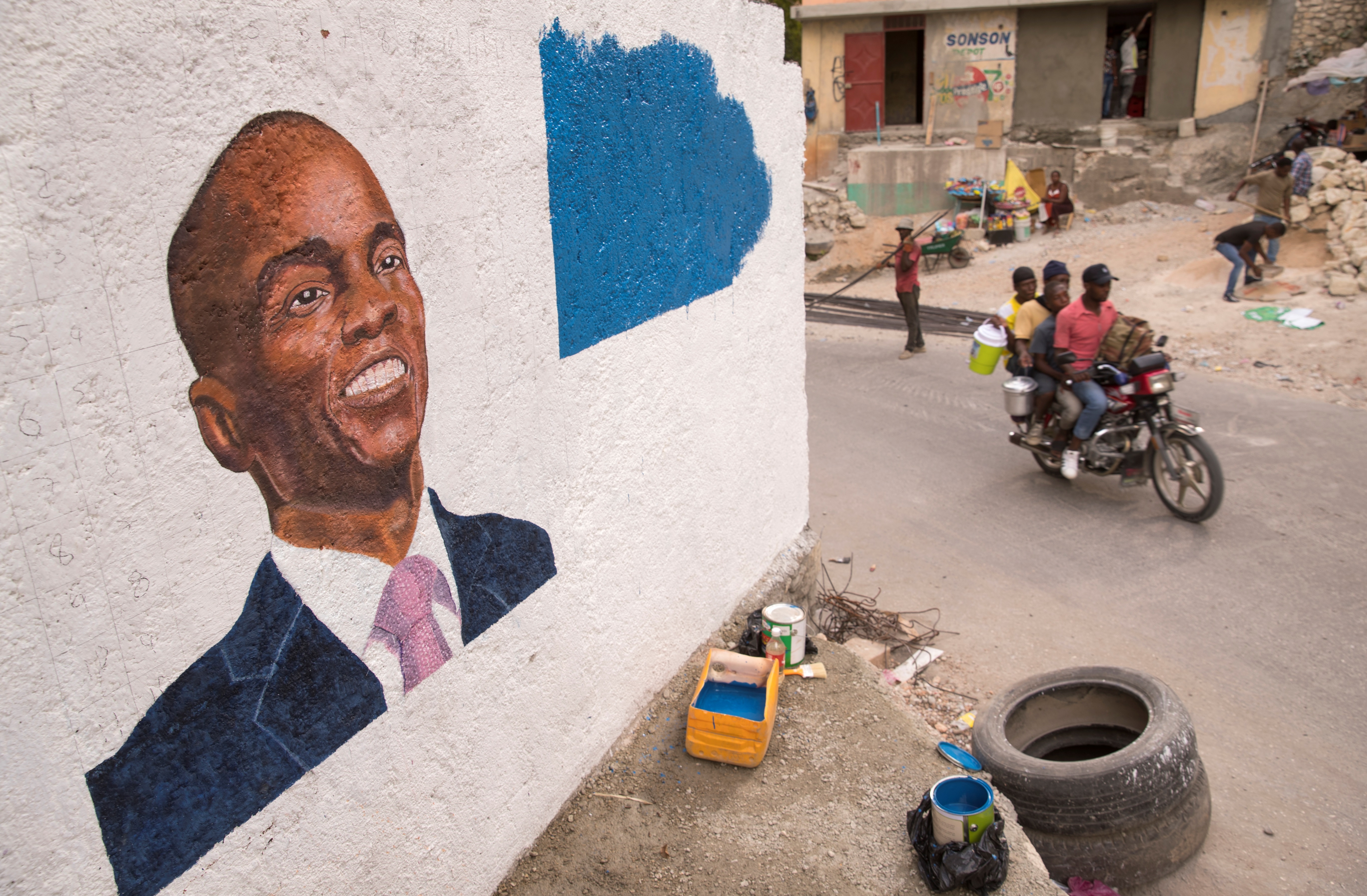 Fotografía de archivo de personas mientras pasan junto a un mural en homenaje al asesinado Jovenel Moise, en Puerto Príncipe (EFE/ Orlando Barría)