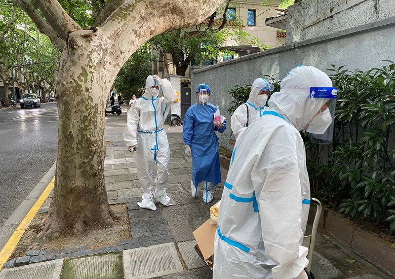FILE PHOTOS - Workers in protective suits walk down a street after the outbreak of the coronavirus disease (COVID-19) in Shanghai, China.  June 9, 2022. (Reuters) / Andrew Galbraith