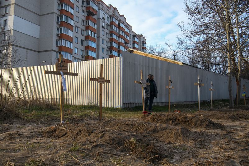 Un hombre en pie junto a las tumbas de varios civiles que, según los residentes locales, fueron asesinados por soldados rusos en Bucha