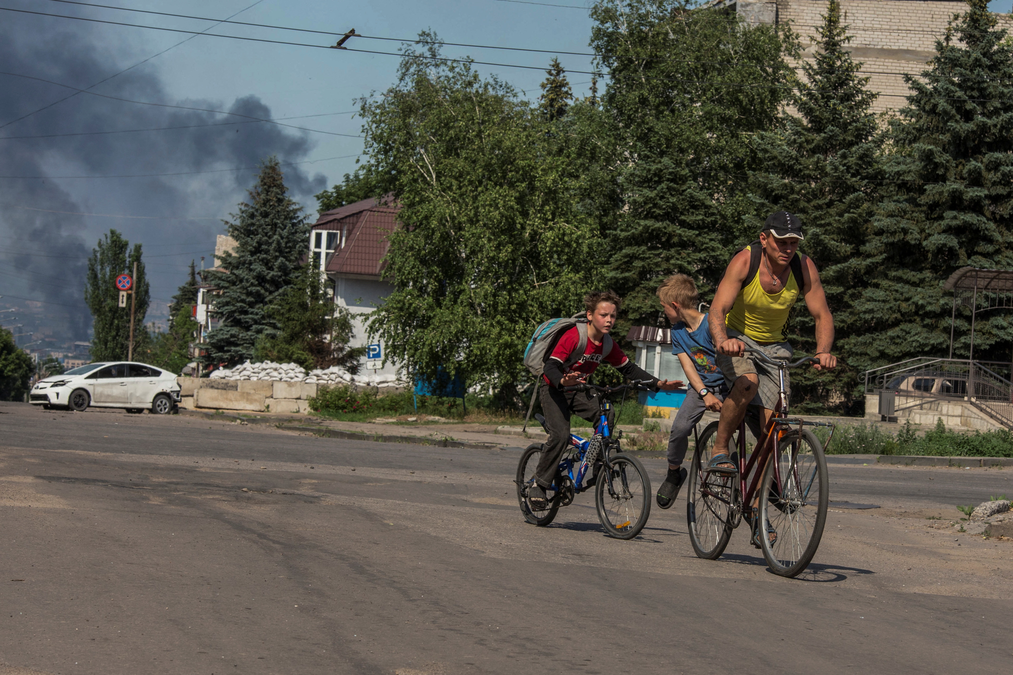 Un hombre escapa junto a sus hijos tras los bombardeos rusos contra la ciudad de Lysychansk, en la región de Lugansk (REUTERS/Oleksandr Ratushniak)