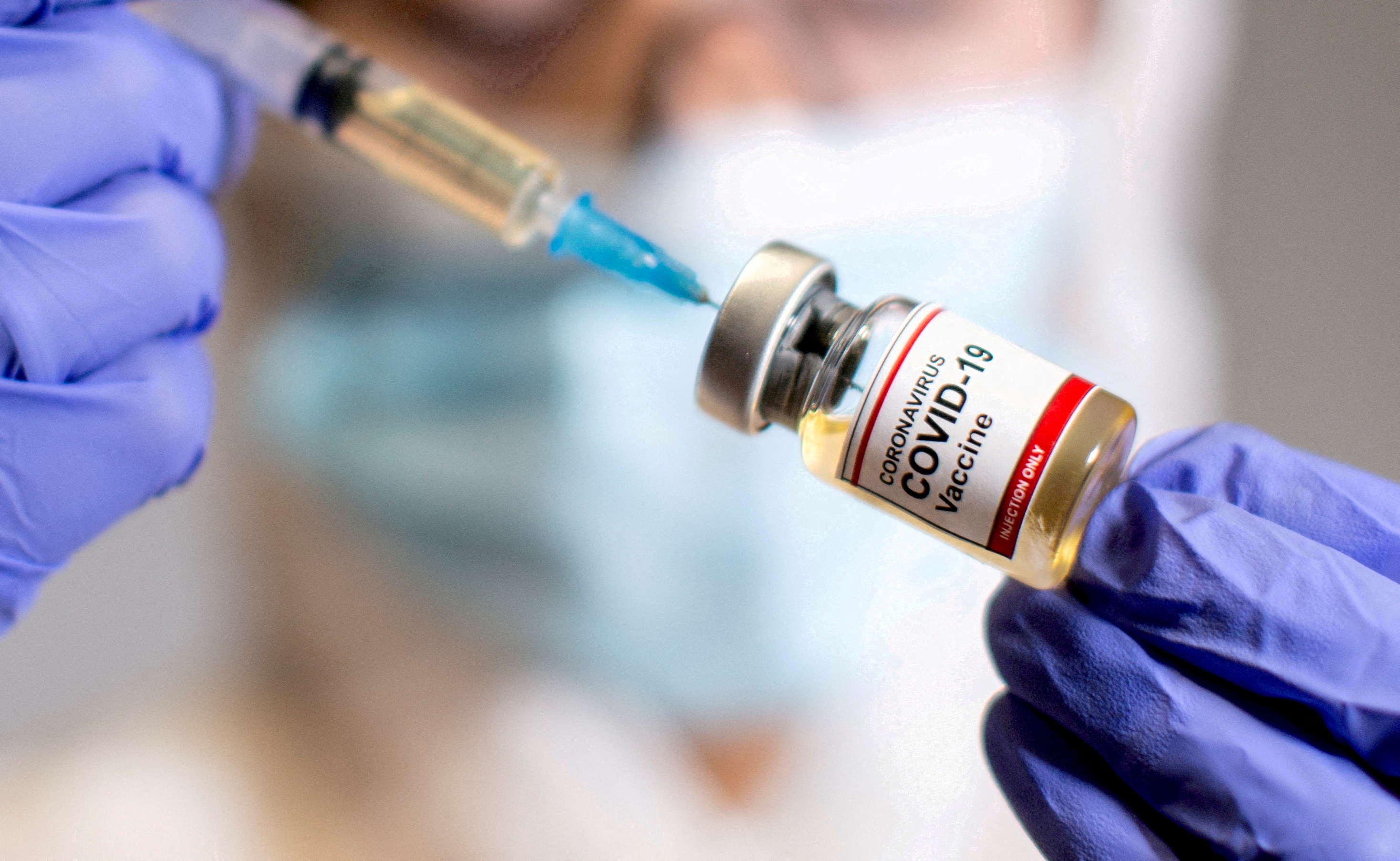 FILE PHOTO: A woman holds a medical syringe and a small bottle labelled "Coronavirus COVID-19 Vaccine
