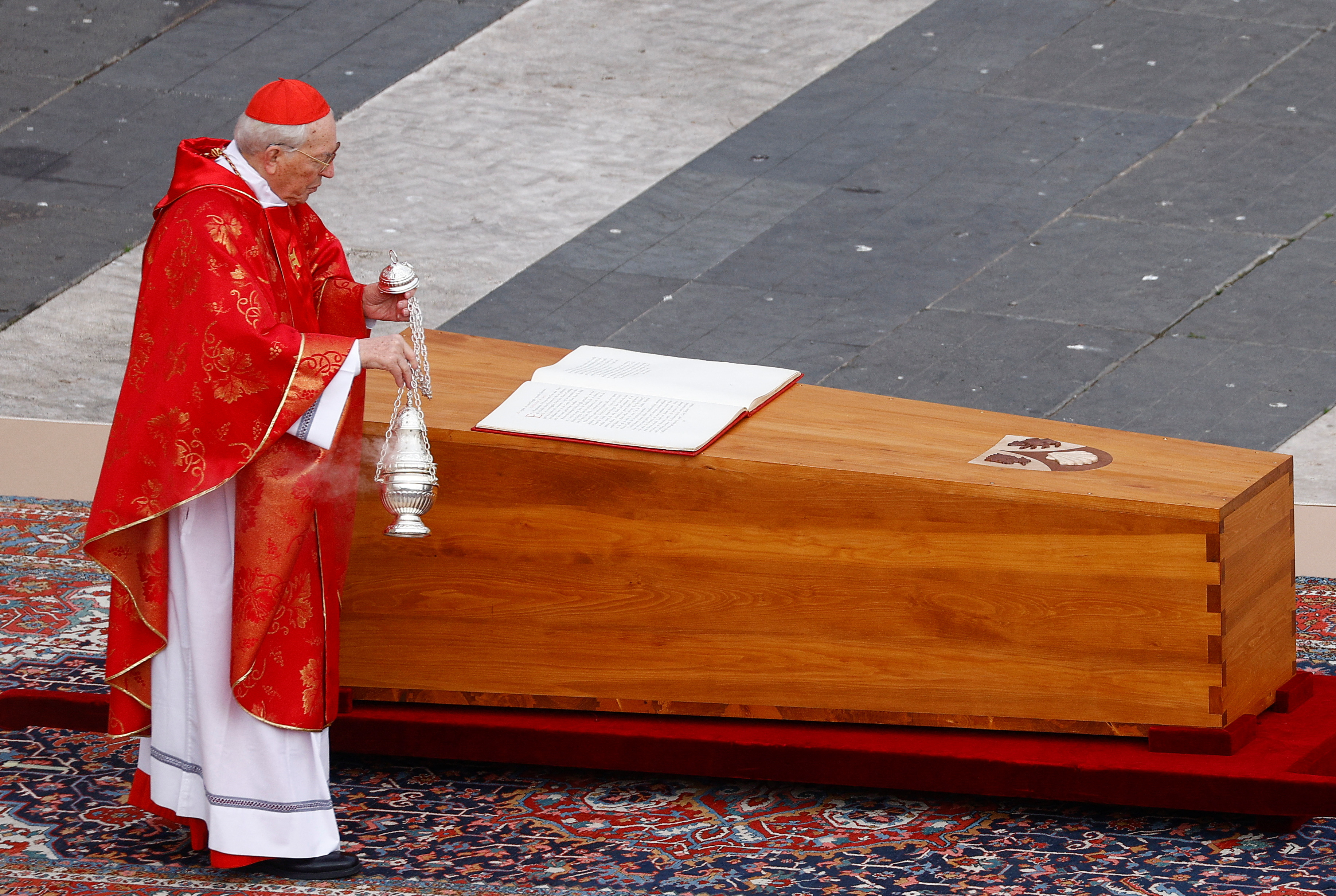 El cardenal Giovanni Battista Re bendice el ataúd de Benedicto con incienzo.
