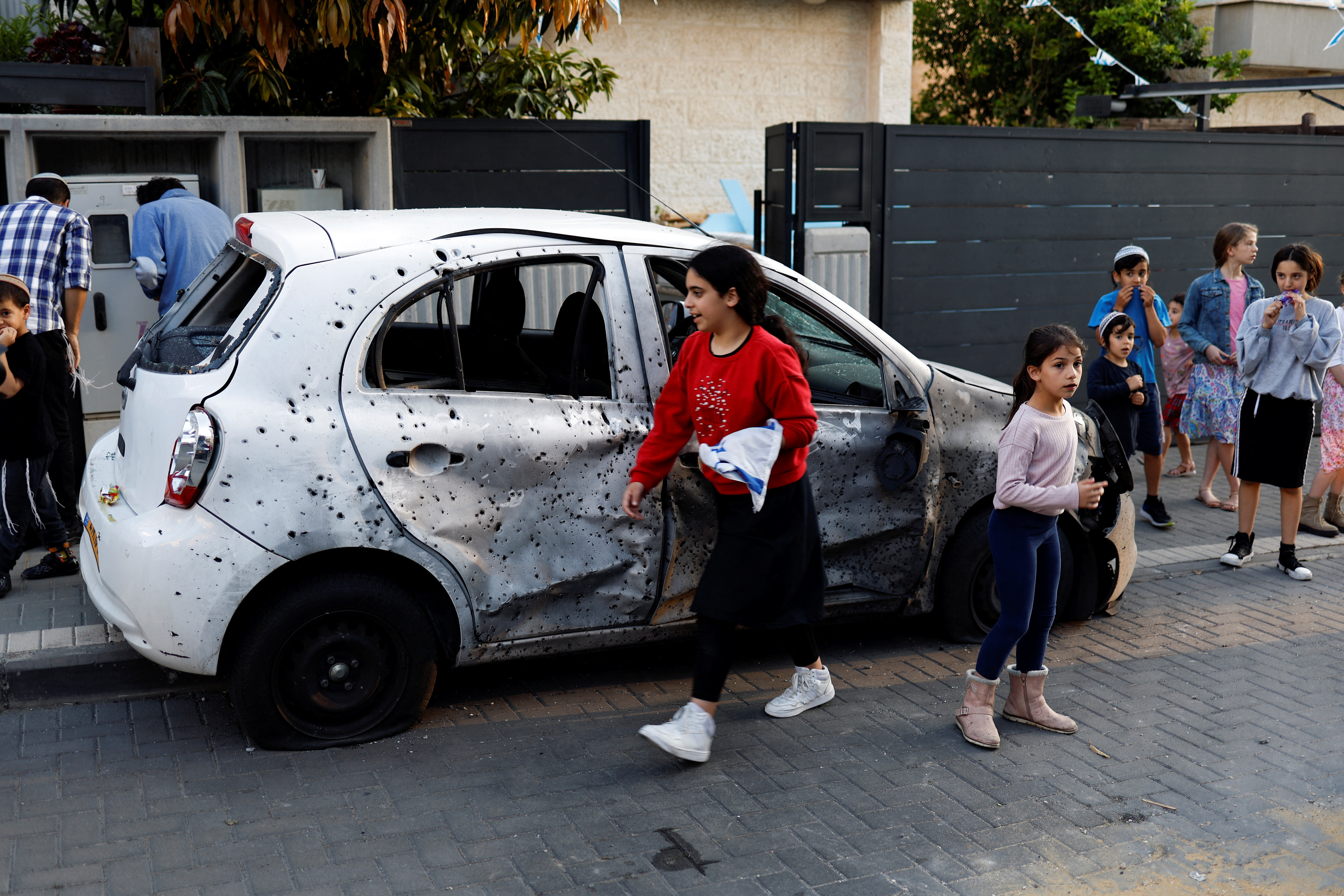 Varias personas se reúnen cerca de un coche dañado tras el impacto de un cohete lanzado desde Gaza en Sderot, sur de Israel, 2 de mayo de 2023. REUTERS/Amir Cohen