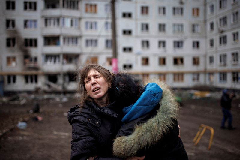 Una mujer reacciona mientras abraza a otra en el exterior de un bloque de apartamentos fuertemente dañado, tras un ataque de artillería en Járkov (Reuters)