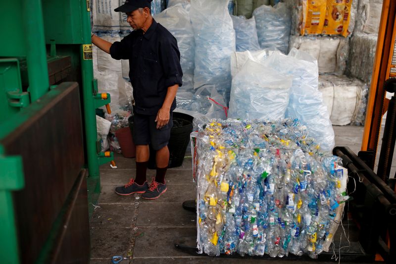 Un hombre comprimiendo plástico reciclado con el que se fabricará fibra para tela en un monasterio en Bangkok (REUTERS/Soe Zeya Tun)