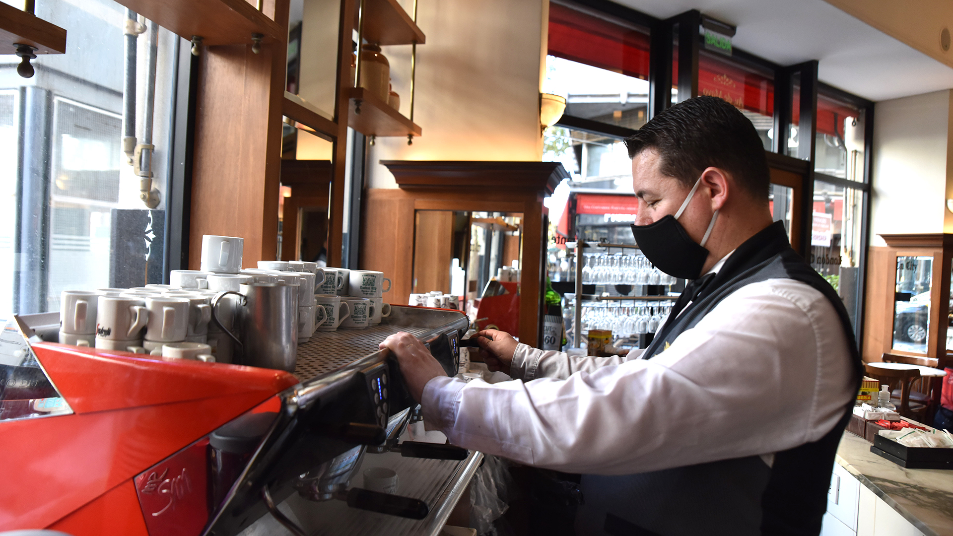 Un mozo de una confitería del centro porteño prepara un café con leche para el delivery