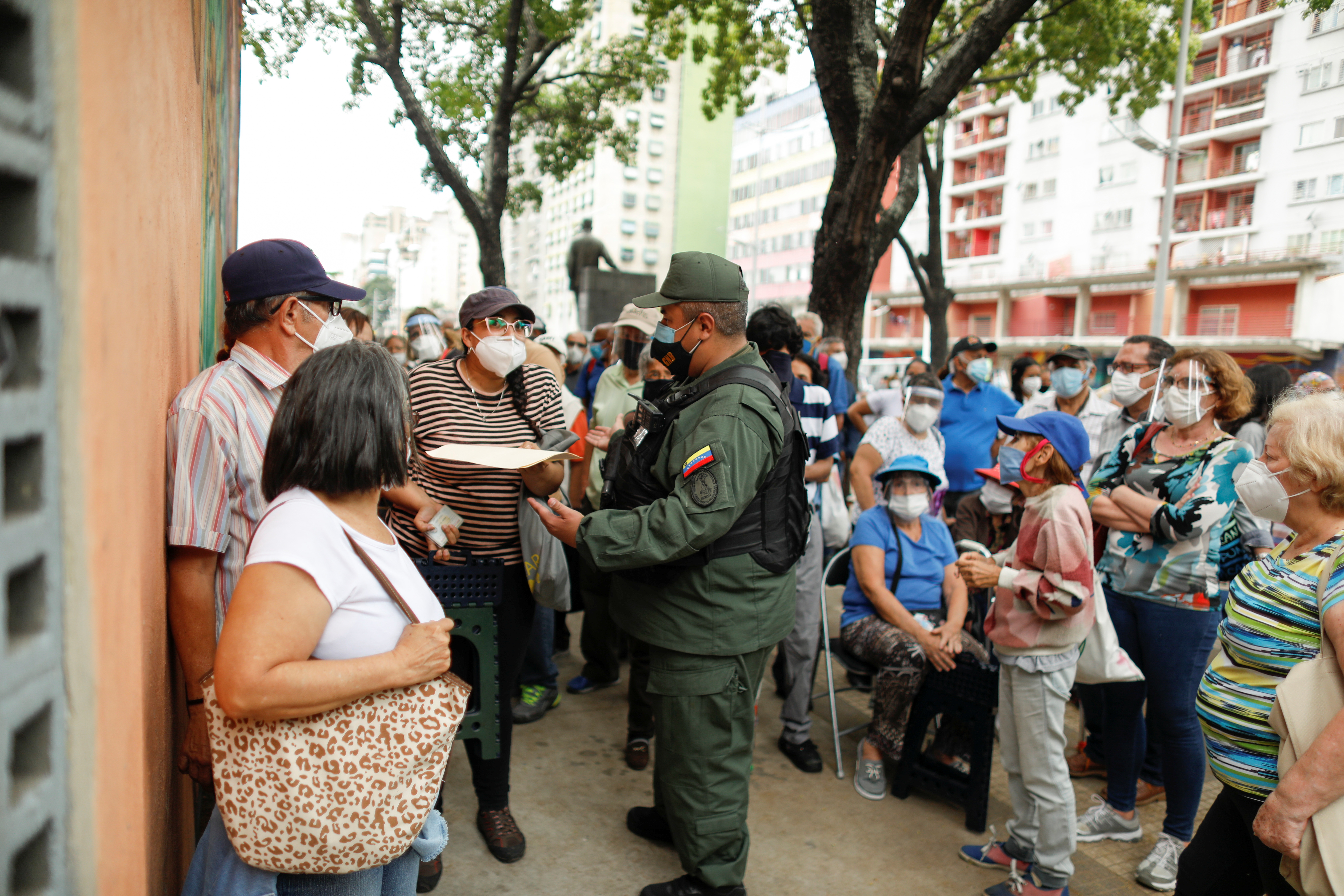 Una mujer discute con un soldado de la Guardia Nacional Bolivariana, mientras ancianos y trabajadores de la salud esperan recibir su primera dosis de la vacuna rusa Sputnik V contra la enfermedad del coronavirus (COVID-19), frente al hotel Alba Caracas. A los que esperan les exigen el "Carnet de la Patria" (Reuters)