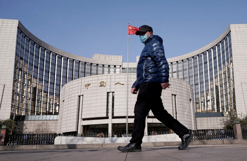 Un hombre con mascarilla delante de la sede del Banco Popular de China, el banco central, en Beijing