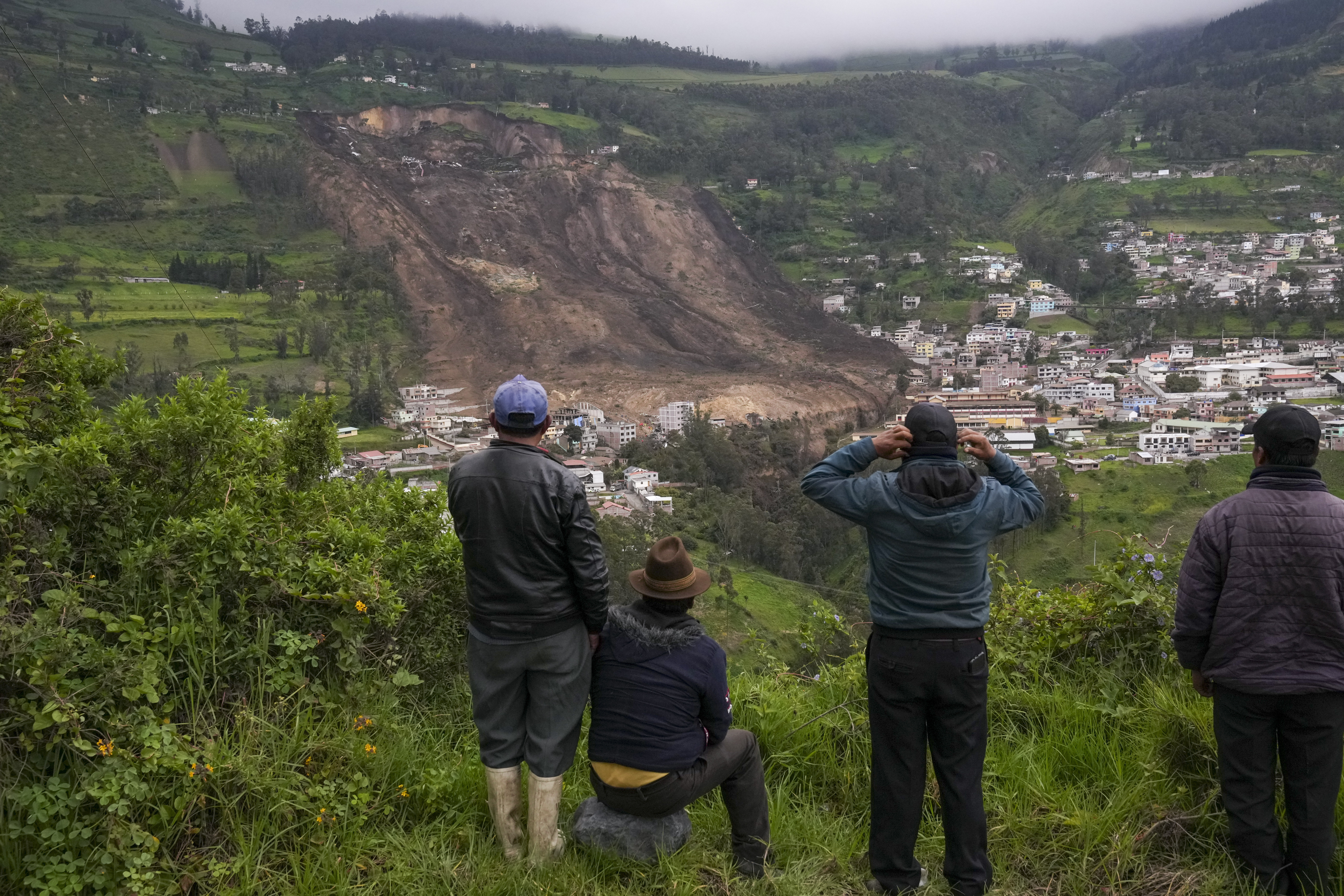 Residentes observan el lugar de un deslizamiento de tierra causado por fuertes lluvias que sepultó decenas de casas en Alausi, Ecuador, el lunes 27 de marzo de 2023. (AP Foto/Dolores Ochoa)