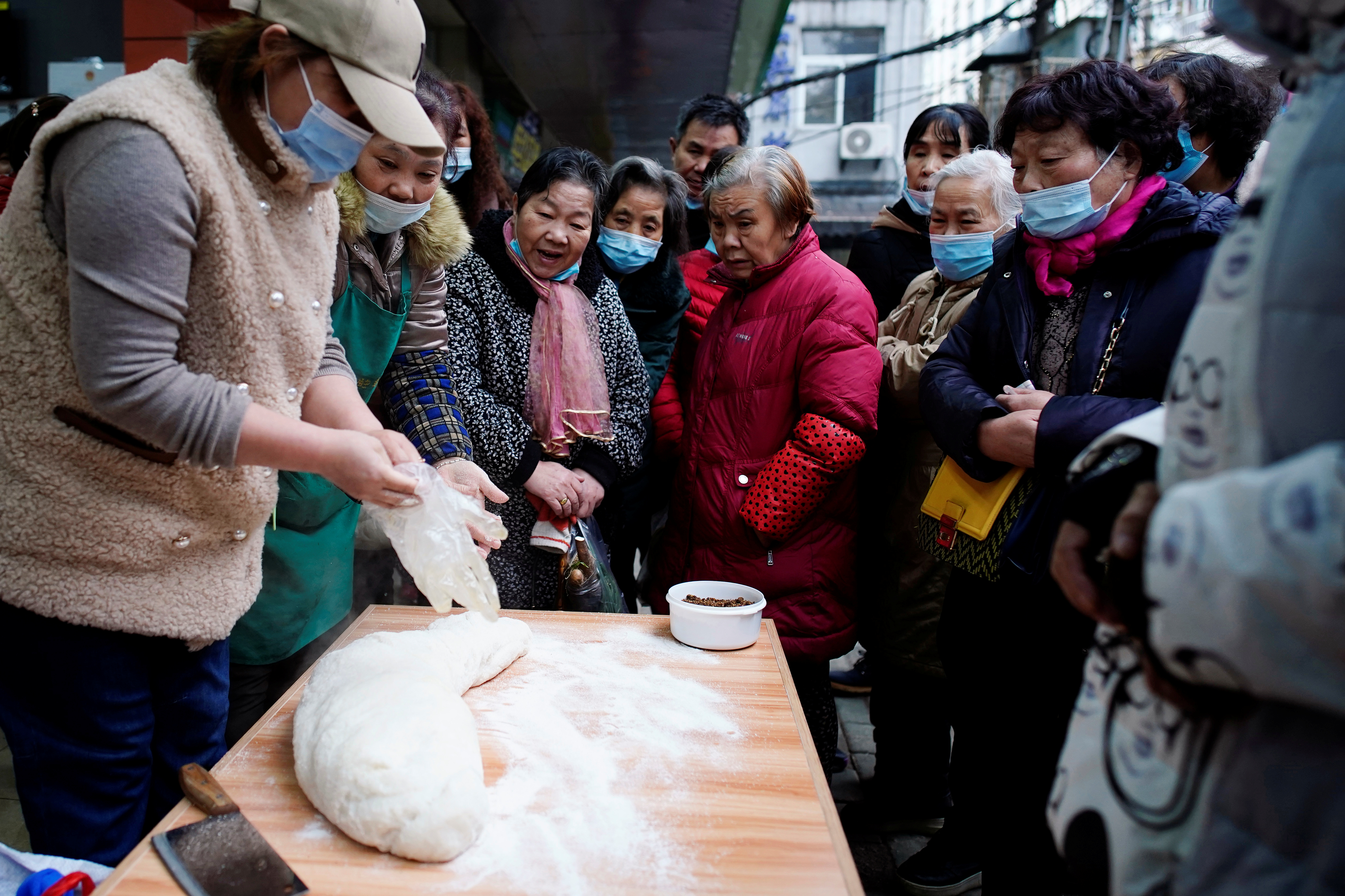 Potenciales clientes se ensimisman frente a un puesto de comida callejera en Wuhan, China (REUTERS/Aly Song)