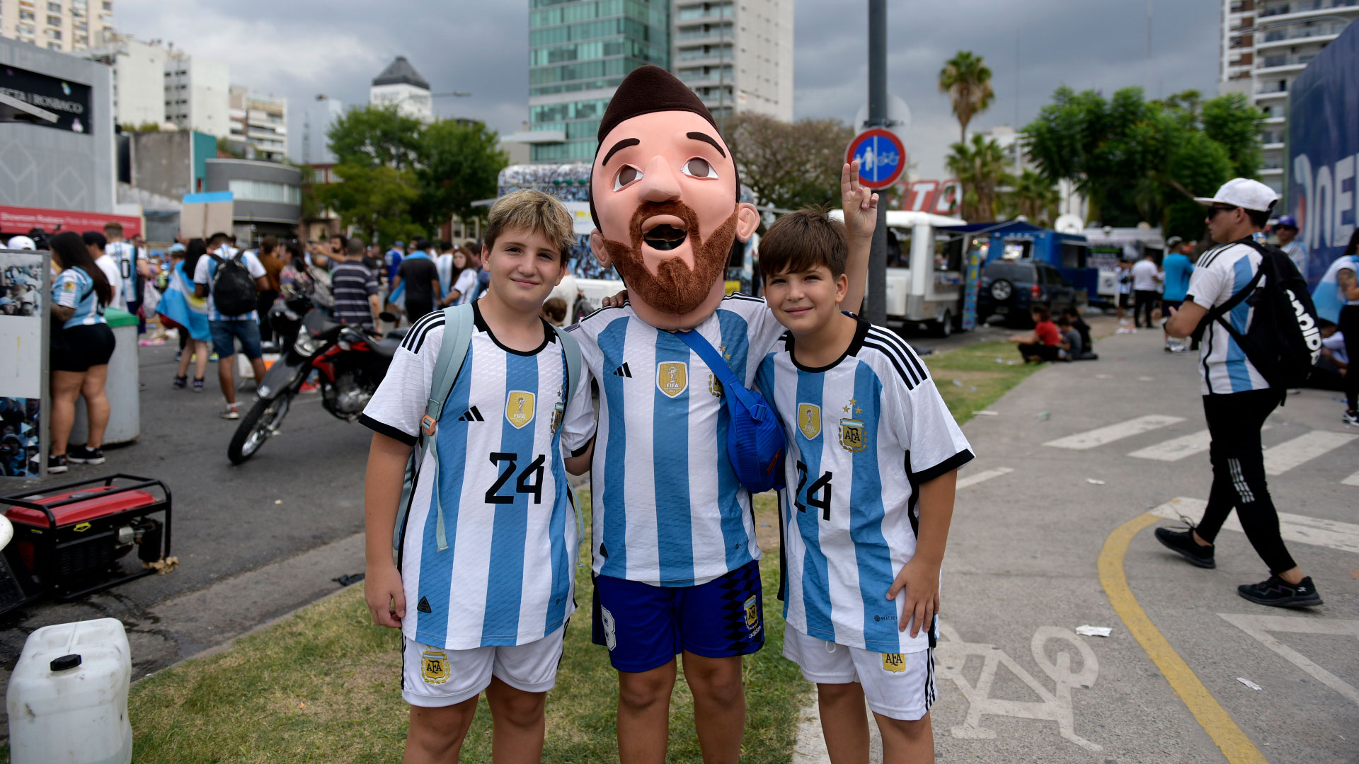 Three fans greet each other, one of them with a giant Messi mask 