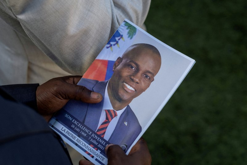 FILE PHOTO: A person holds a photo of the late Haitian President Jovenel Moise, who was assassinated earlier this month, during his funeral at his family home in Cap Haitien, Haiti.  July 23, 2021. REUTERS/Ricardo Arduengo