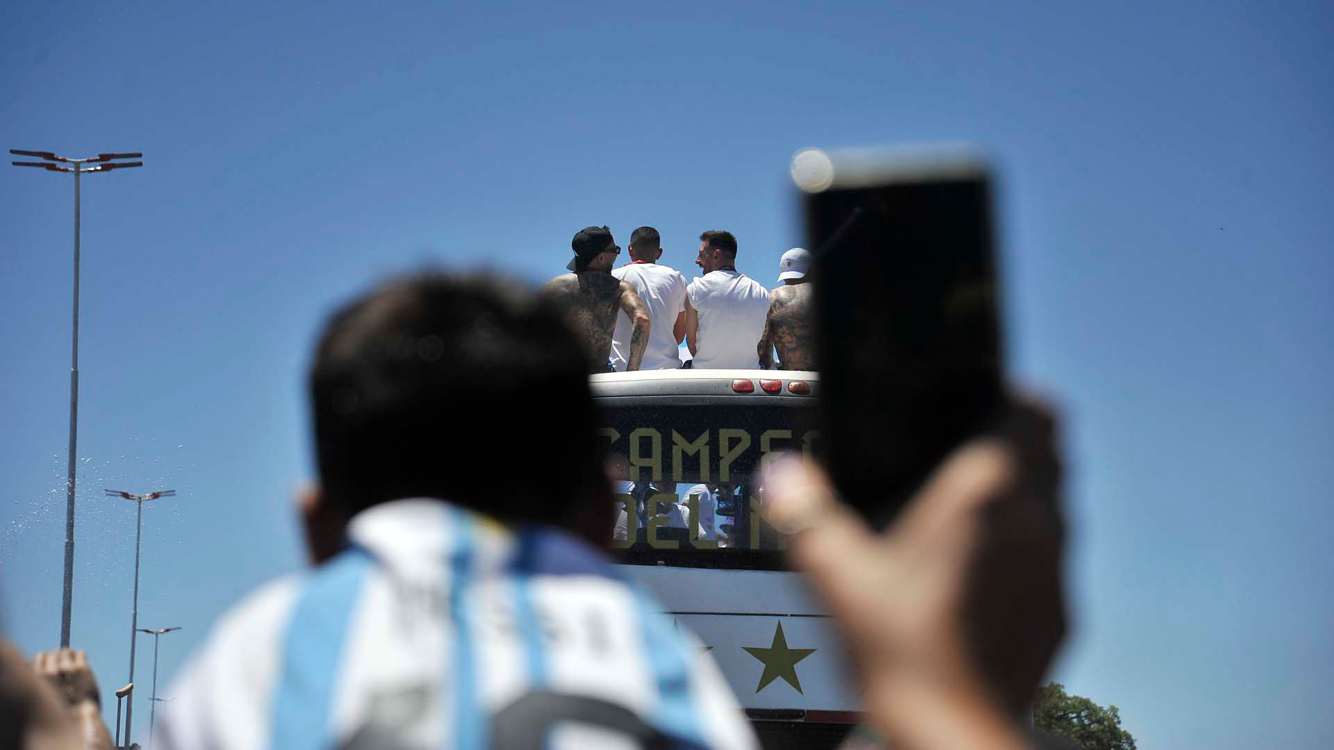 Un simpatizante intenta filmar a Messi y compañeros al paso del vehículo albiceleste. Gustavo Gavotti