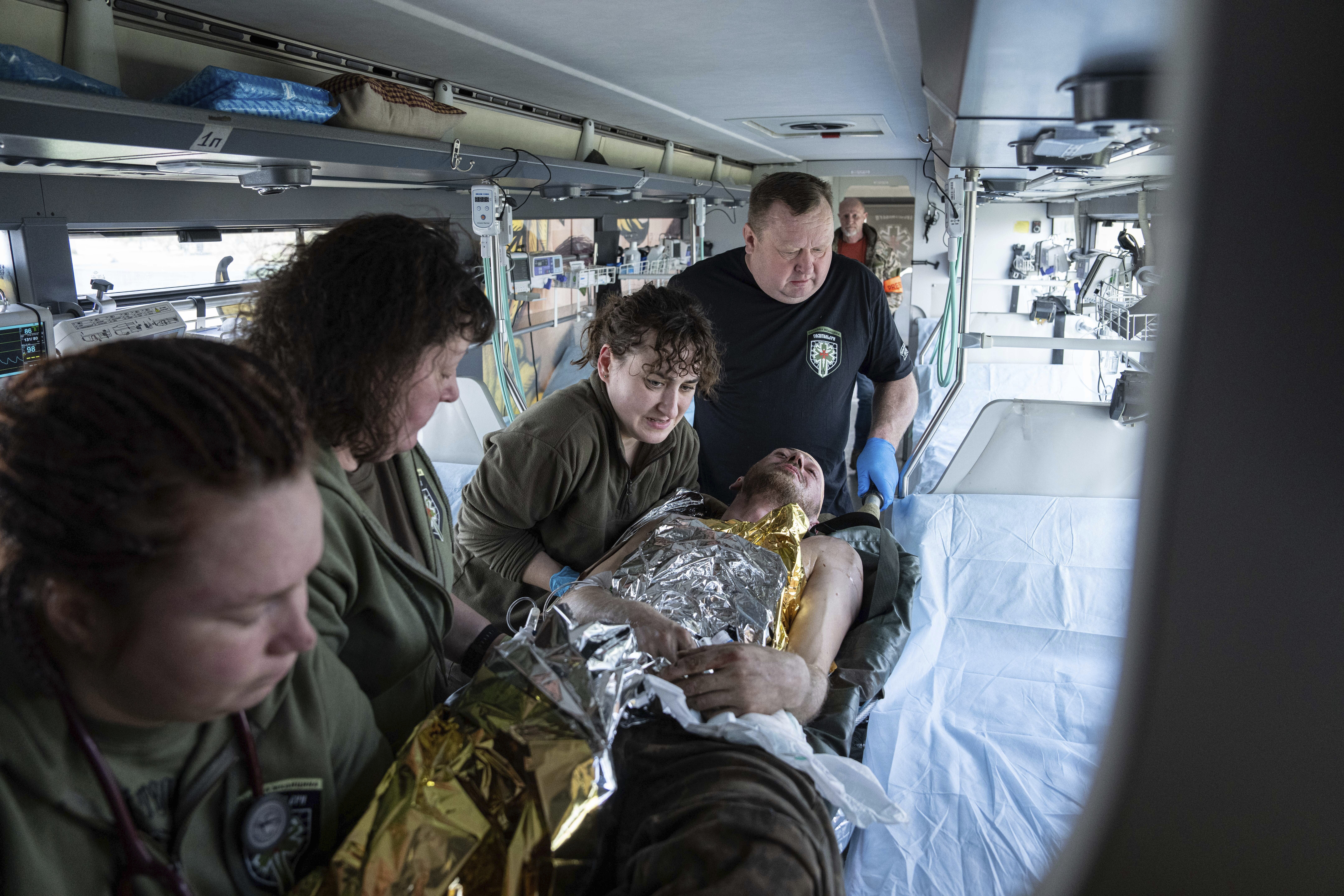 Voluntarios de la organización paramédica Hospitallers mueven a un soldado ucraniano en un autobús medicalizado durante una evacuación en la región de Donetsk, Ucrania, el miércoles 22 de marzo de 2023. (AP Foto/Evgeniy Maloletka)