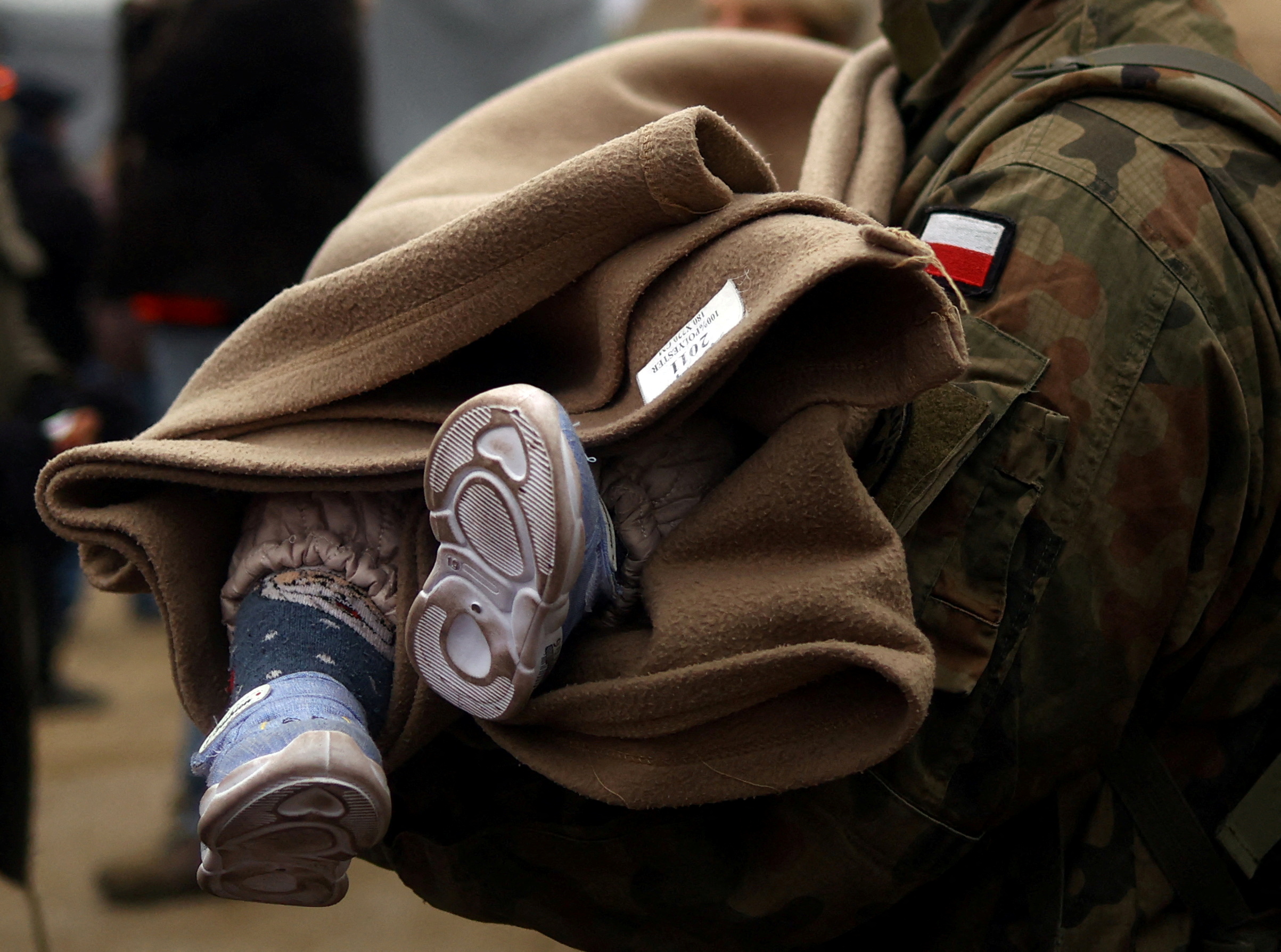 Un soldado polaco lleva a un bebé en el paso fronterizo entre Ucrania y Polonia, en medio de la invasión rusa de Ucrania en Medyka )REUTERS/Hannah McKay/Archivo)