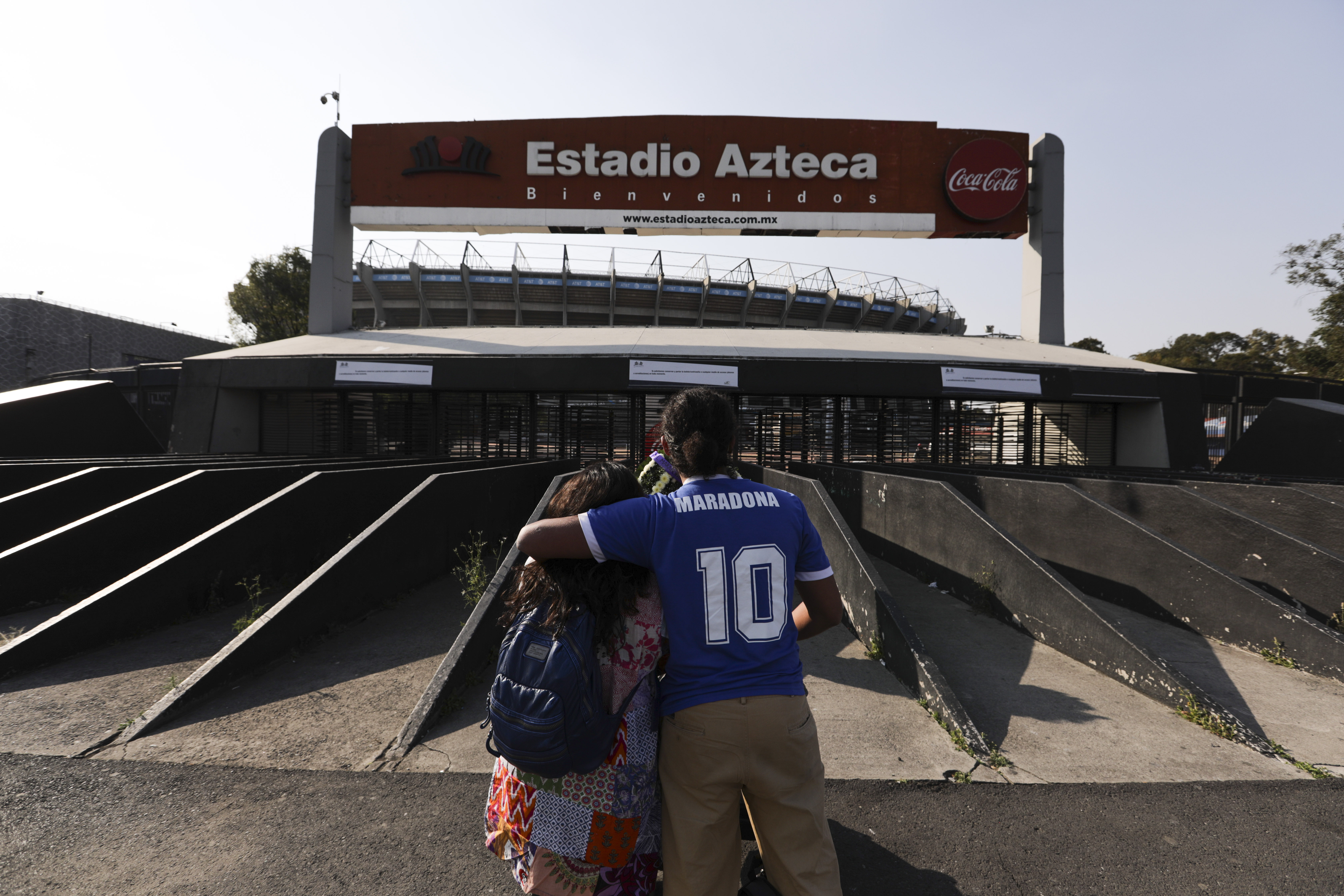 Una pareja, uno de ellos con la camiseta número 10 de Diego Maradona, se abraza en la entrada del estadio Azteca en la Ciudad de México, el miércoles 25 de noviembre de 2020.