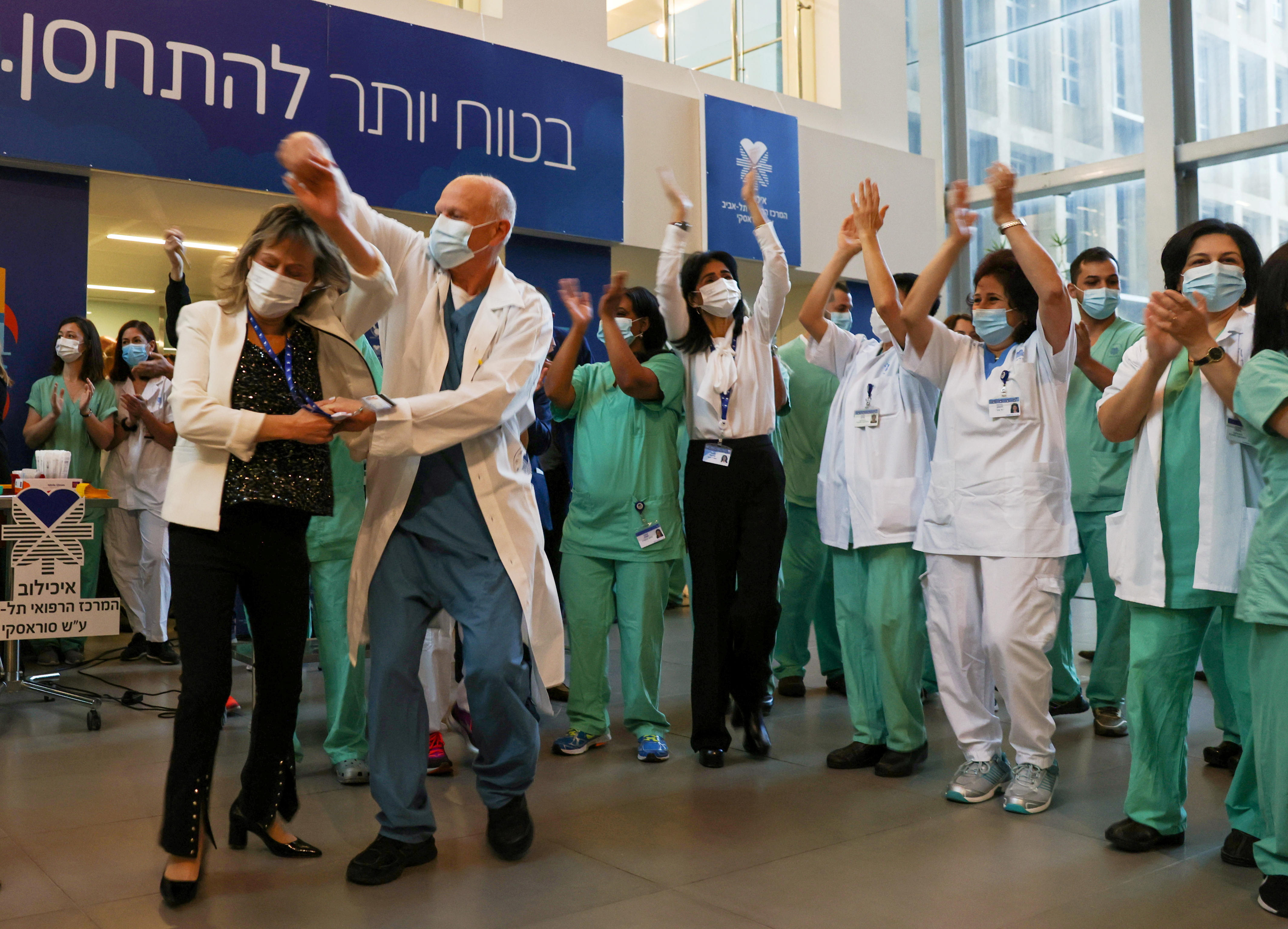 Profesionales de la salud celebran luego de recibir la vacuna contra el COVID-19 en un hospital de Tel Aviv, Israel (REUTERS/Ronen Zvulun)
